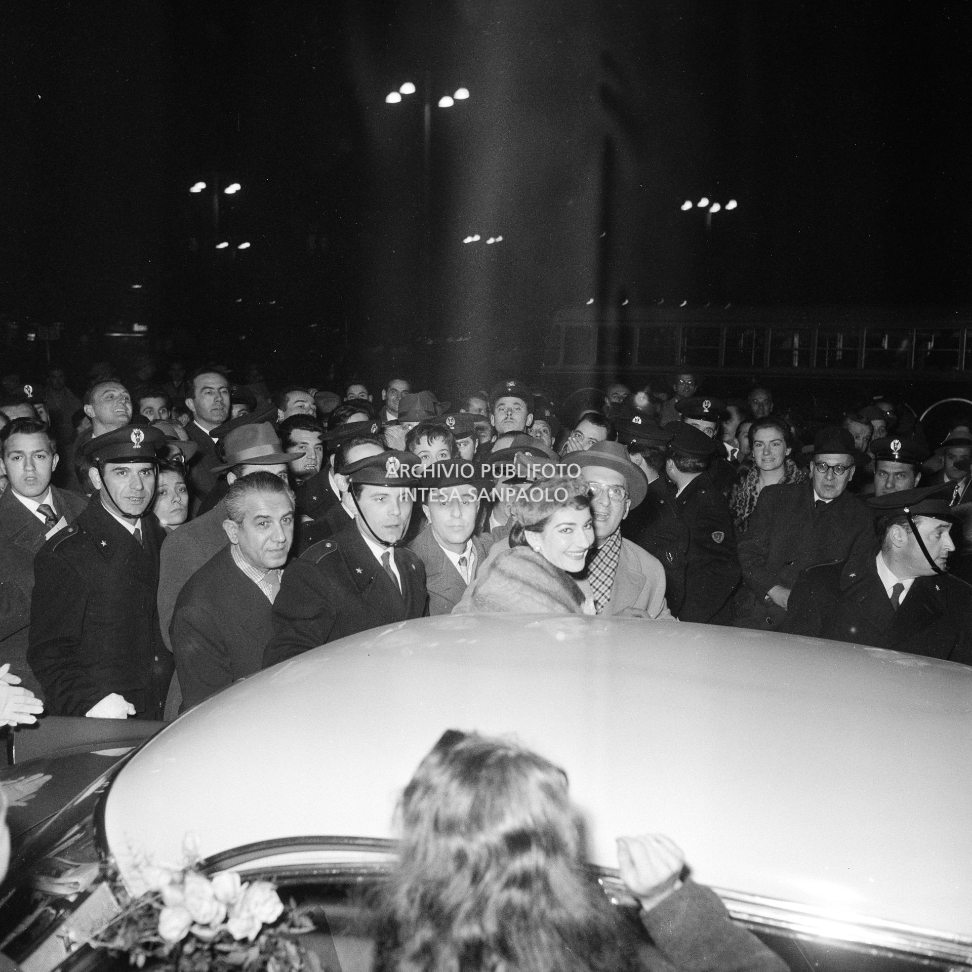 Maria Callas alla Stazione Centrale di Milano, al suo rientro da Roma, si avvia, tra la folla accorsa per accoglierla, all'automobile che la attende