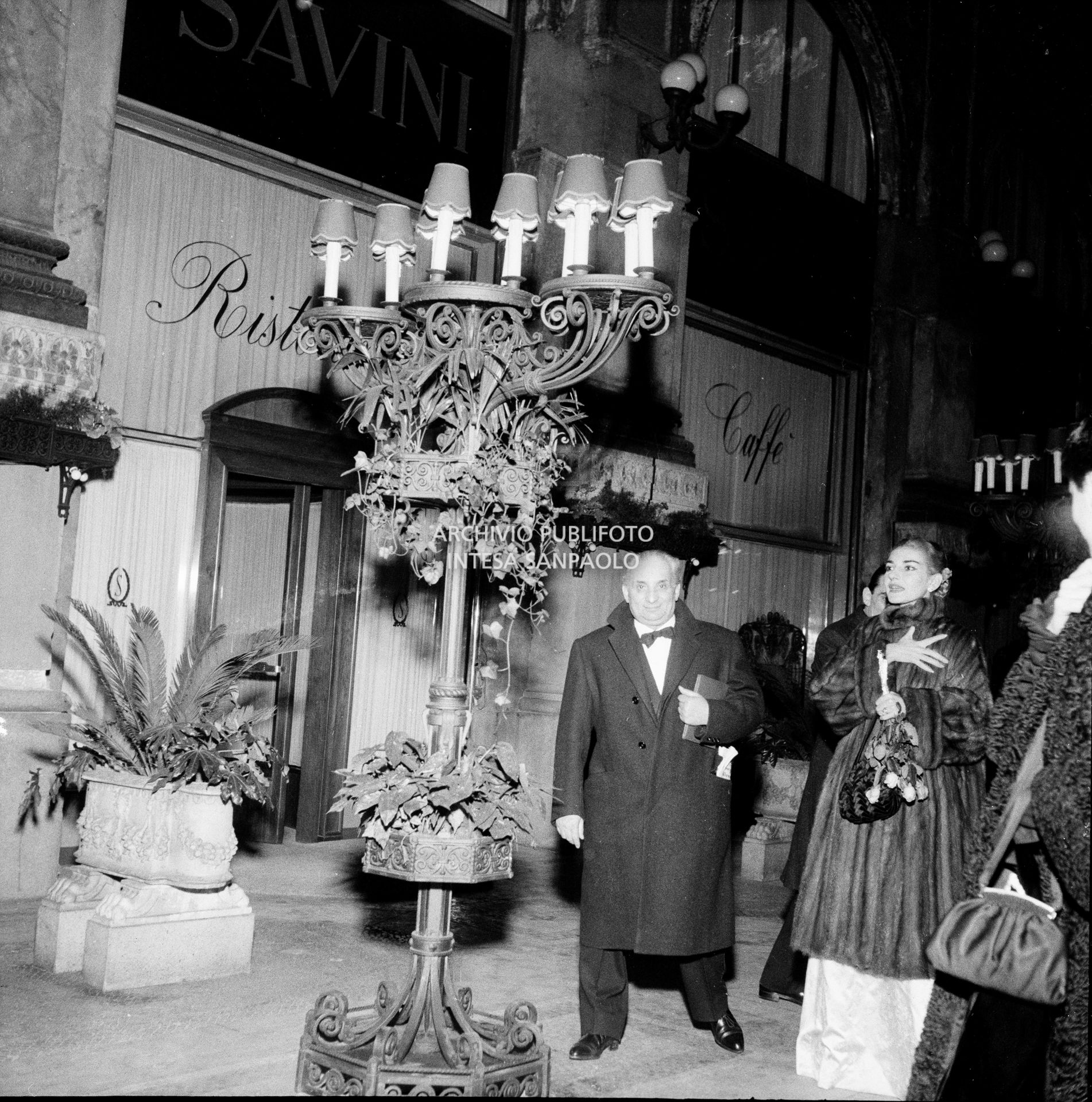 Maria Callas con il marito Giovanni Battista Meneghini si avvia al ristorante Savini di Milano, in Galleria, dopo aver cantato alla serata inaugurale della stagione lirica del Teatro alla Scala con la Vestale di Gaspare Spontini