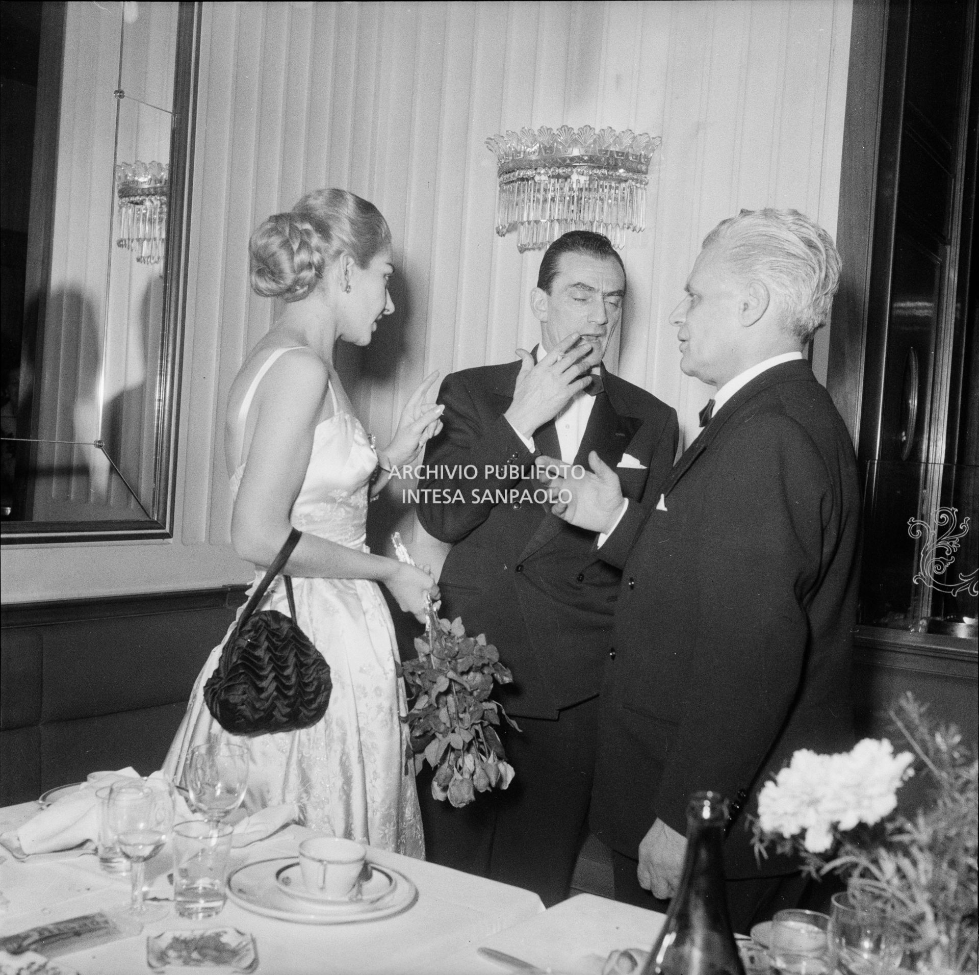 Maria Callas al ristorante Savini di Milano, la sera della Prima della Vestale di Gaspare Spontini, in compagnia del regista Luchino Visconti e del soprintendente del Teatro alla Scala Antonio Ghiringhelli