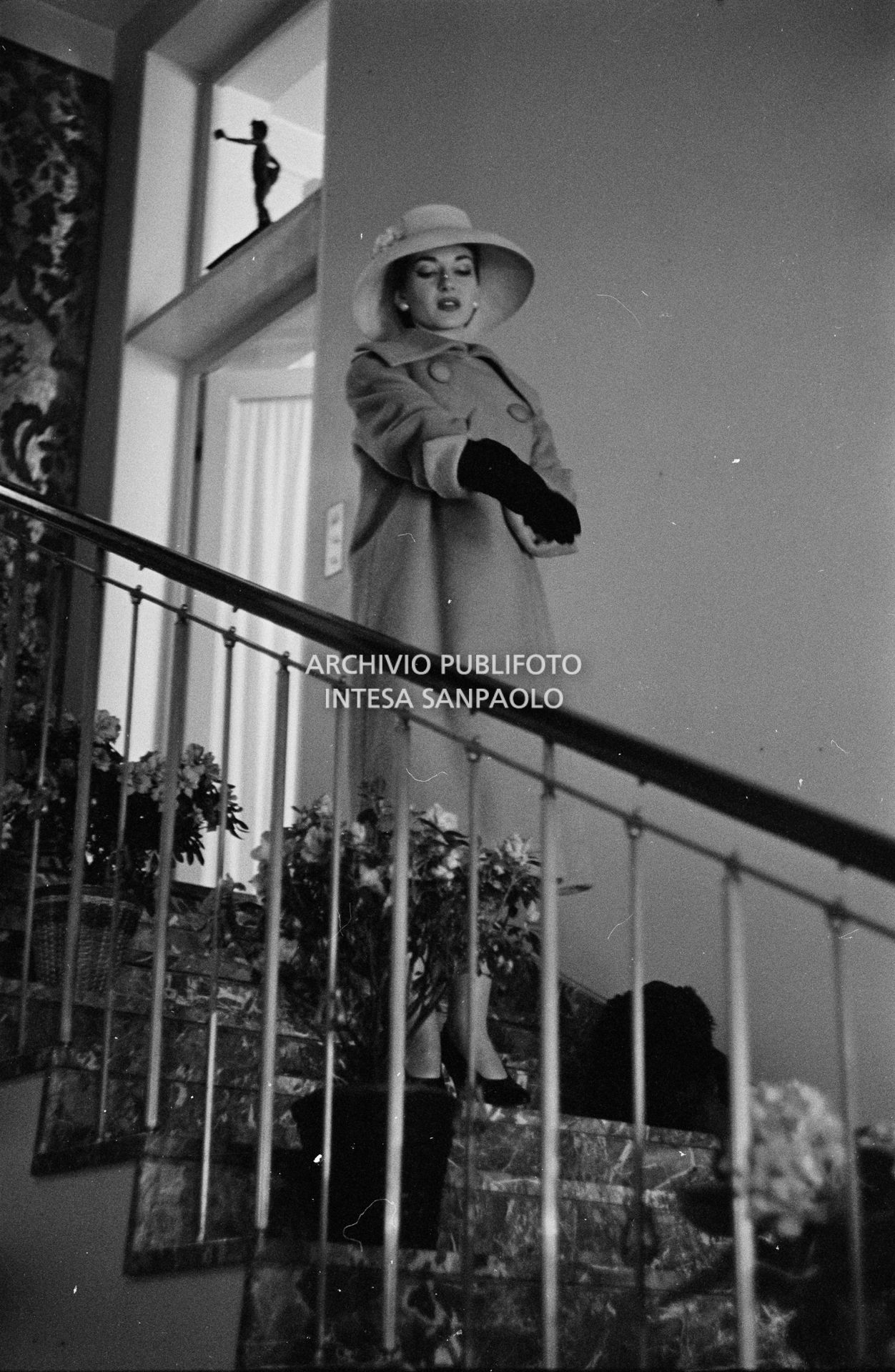 Maria Callas, ritratta in posa sulle scale della sua abitazione, indossa abito e cappello della sartoria Biki