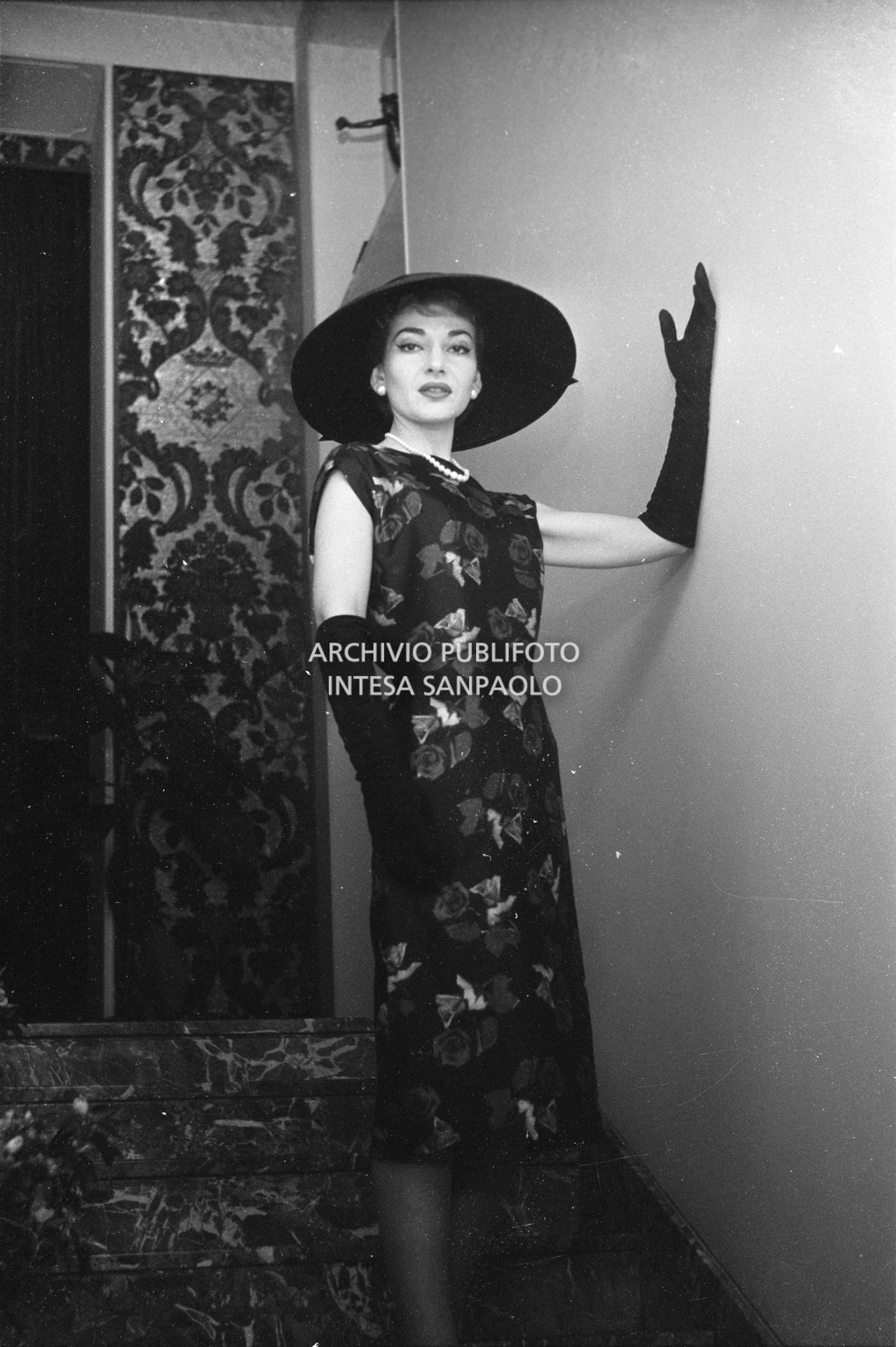 Maria Callas, ritratta nella sua abitazione, indossa abito e cappello della sartoria Biki