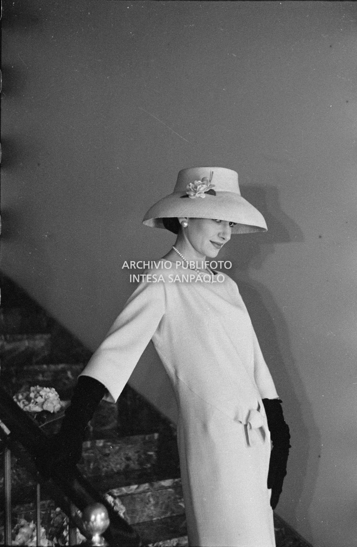Maria Callas, ritratta in posa sulle scale della sua abitazione, indossa abito e cappello della sartoria Biki