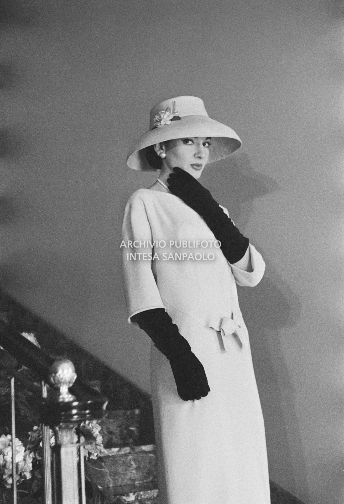 Maria Callas, ritratta in posa sulle scale della sua abitazione, indossa abito e cappello della sartoria Biki