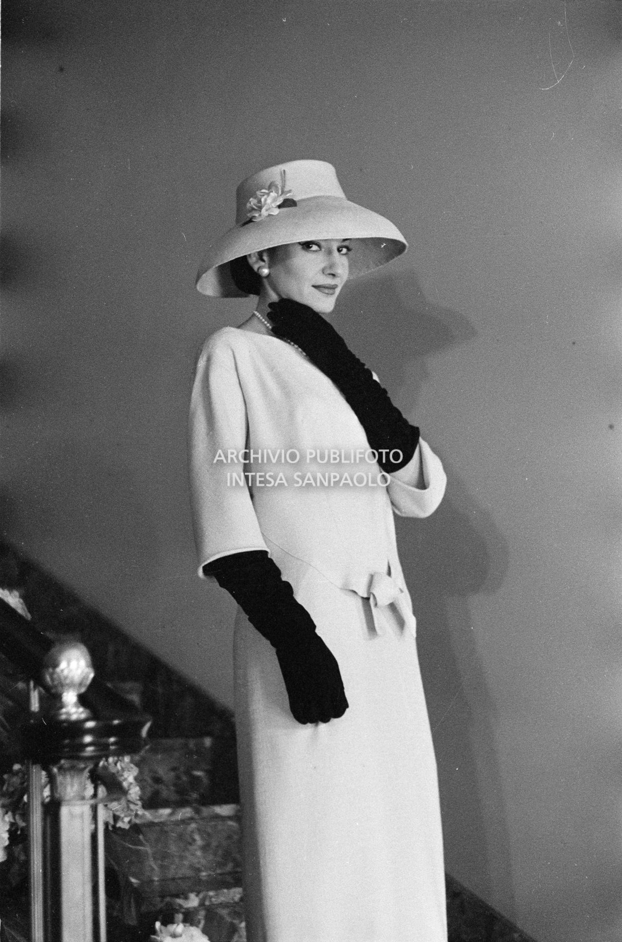 Maria Callas, ritratta in posa sulle scale della sua abitazione, indossa abito e cappello della sartoria Biki