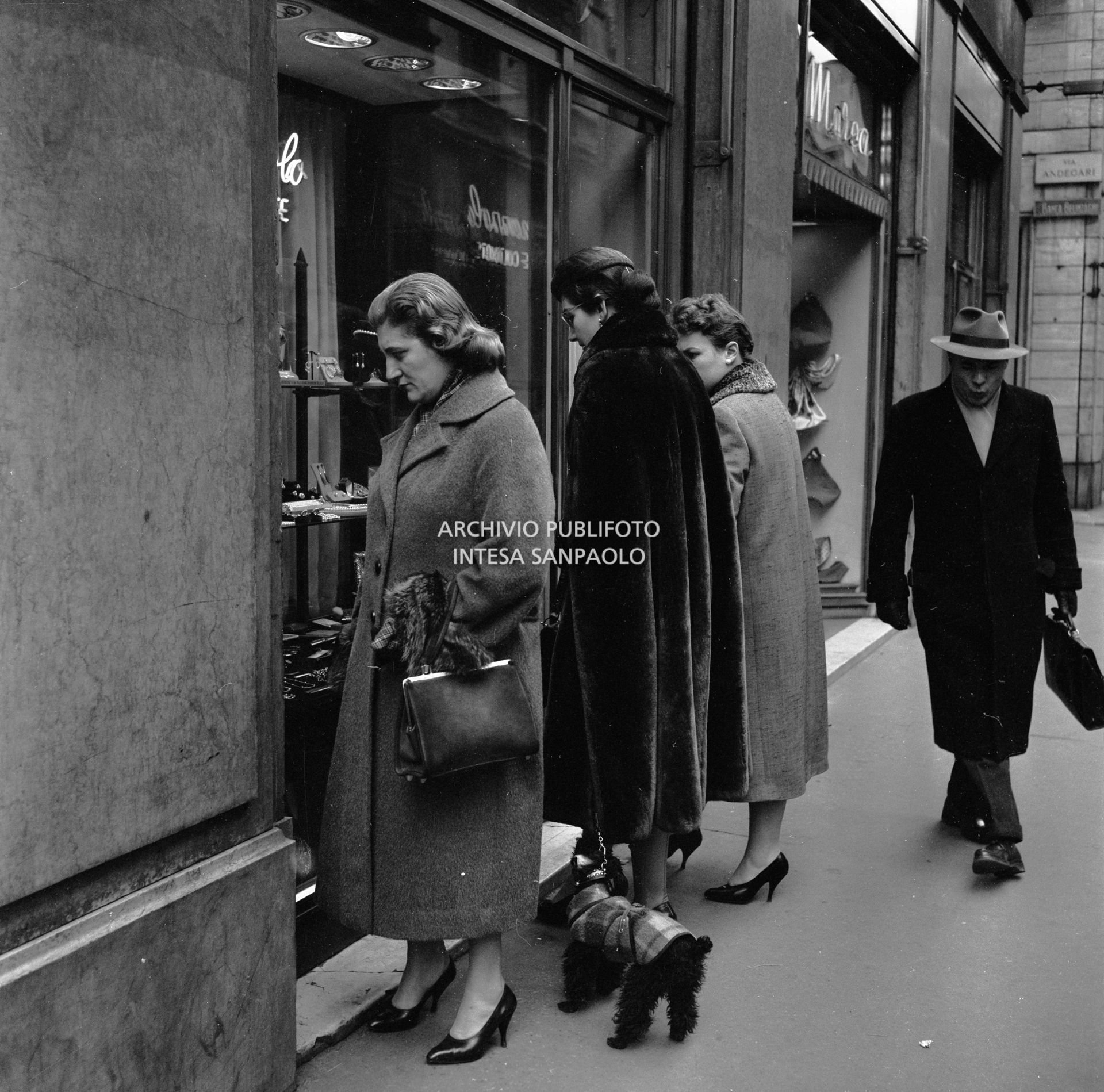 Maria Callas con il suo barboncino guarda una vetrina in via Manzoni a Milano, in compagnia della sua segretaria
