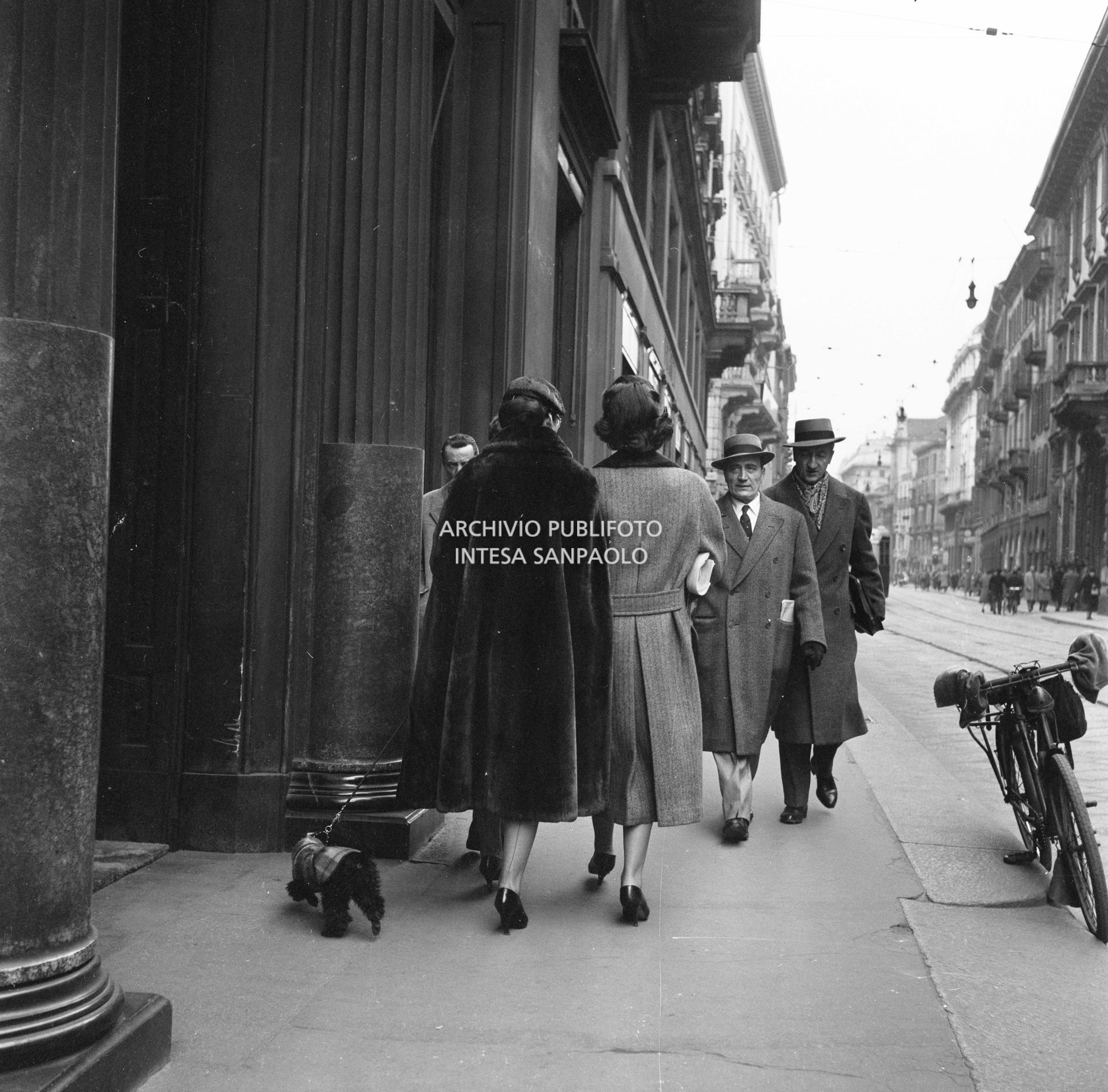 Maria Callas, con il suo barboncino, ripresa di spalle mentre passeggia in via Manzoni, a Milano, con l'amica Giovanna Lomazzi