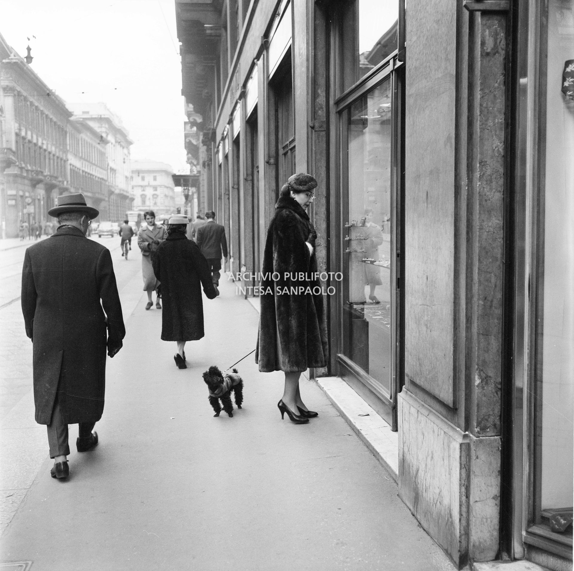 Maria Callas, con il suo barboncino, guarda una vetrina in via Manzoni a Milano