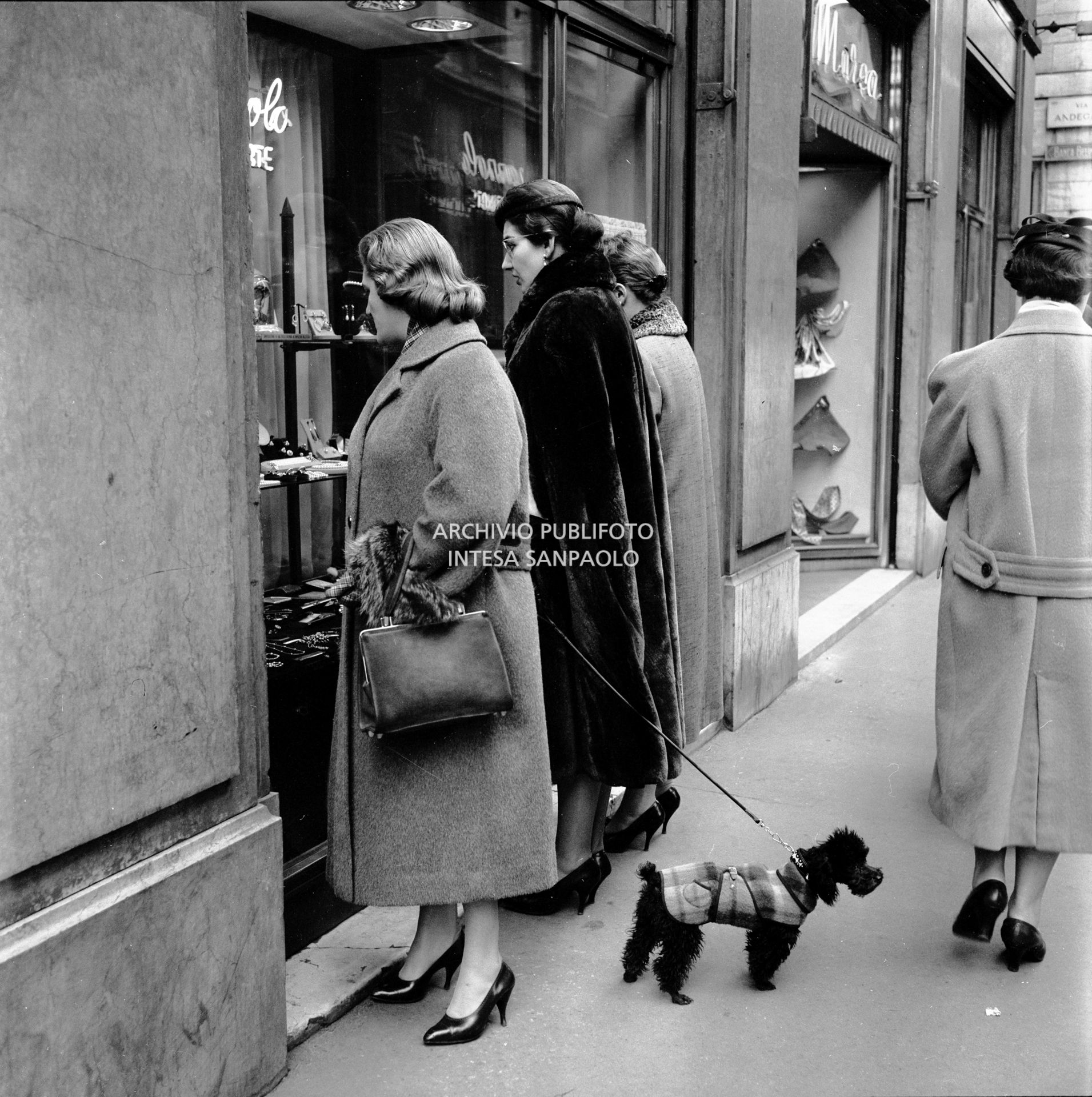 Maria Callas, con il suo barboncino, guarda una vetrina in via Manzoni a Milano