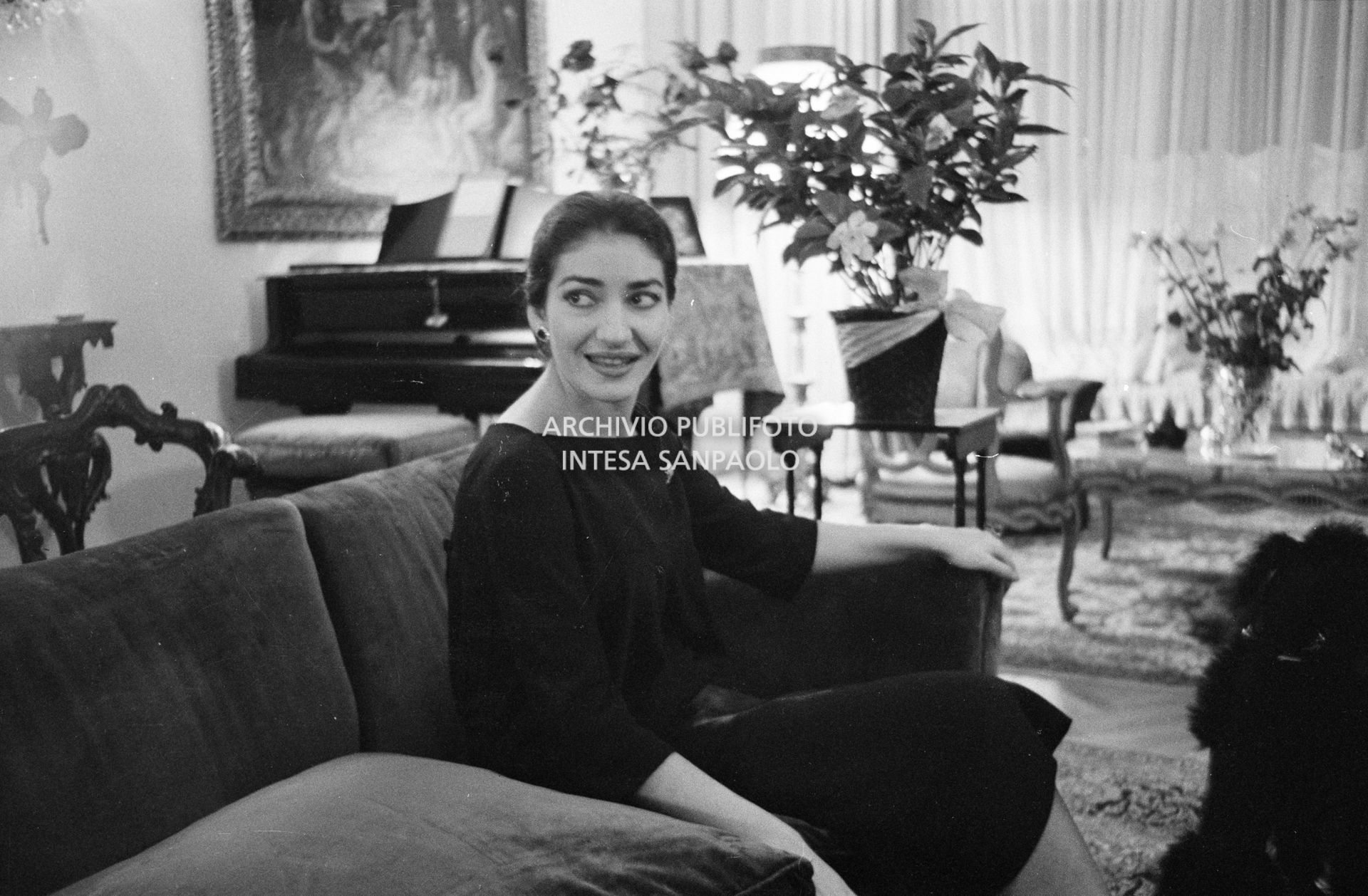Maria Callas, ritratta nella sua abitazione, seduta sul divano in salotto
