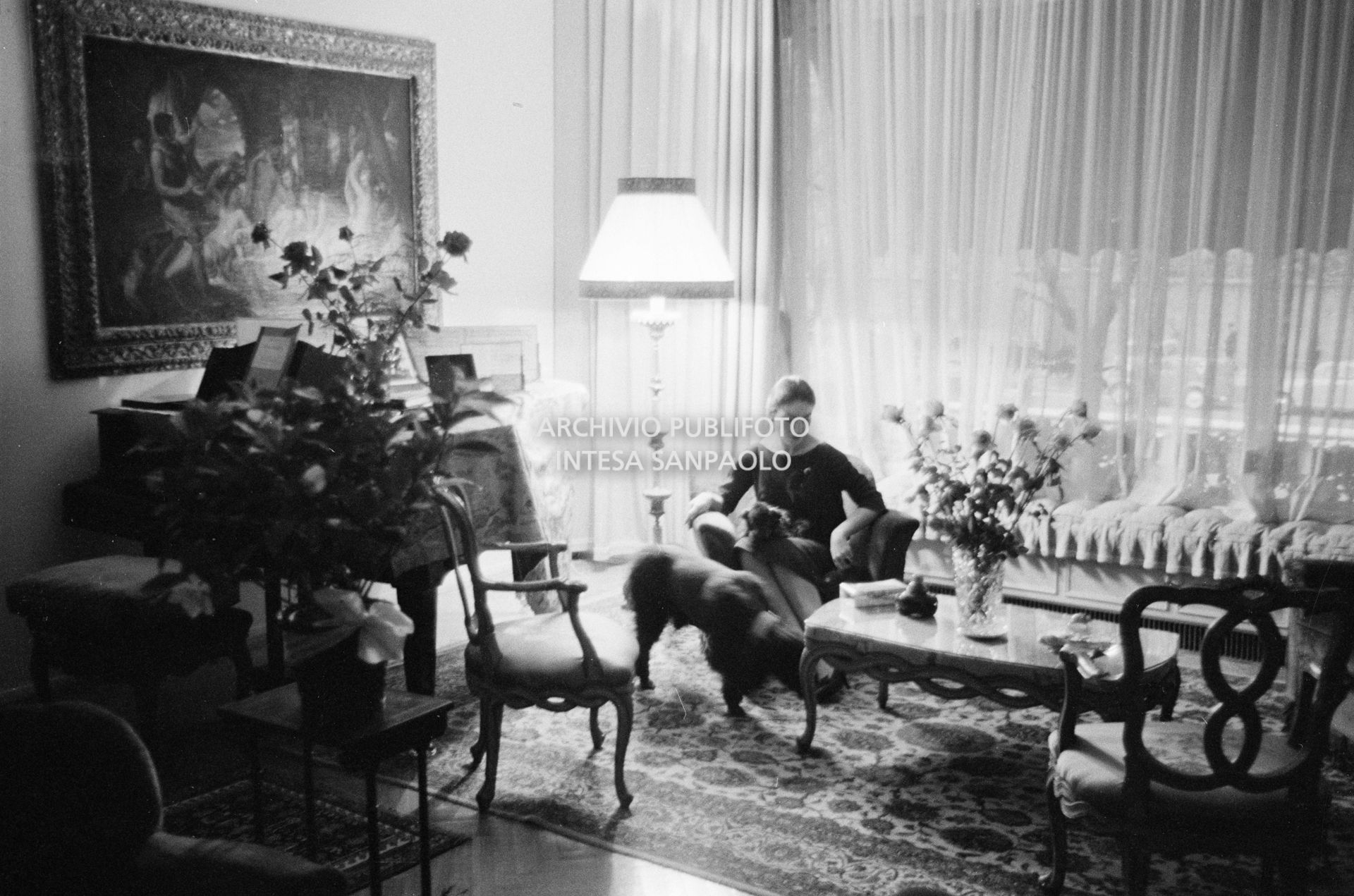 Maria Callas seduta in poltrona, nel salotto della sua abitazione, con i suoi cani