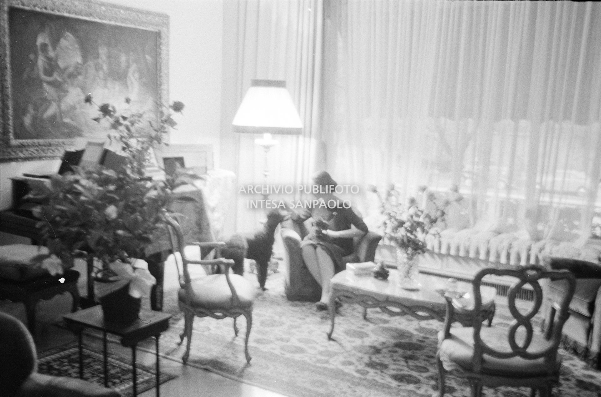 Maria Callas seduta in poltrona, nel salotto della sua abitazione, con i suoi cani