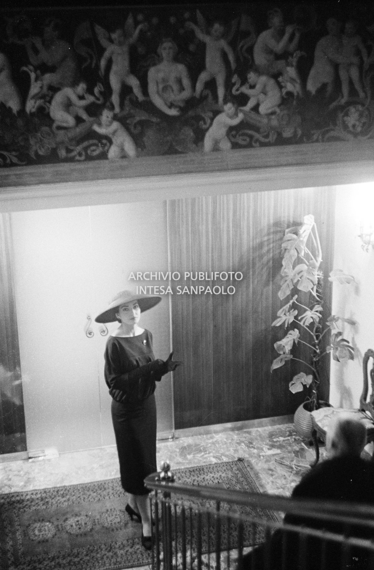 Maria Callas, ritratta nella sua abitazione, indossa un abito e un cappello della sartoria Biki