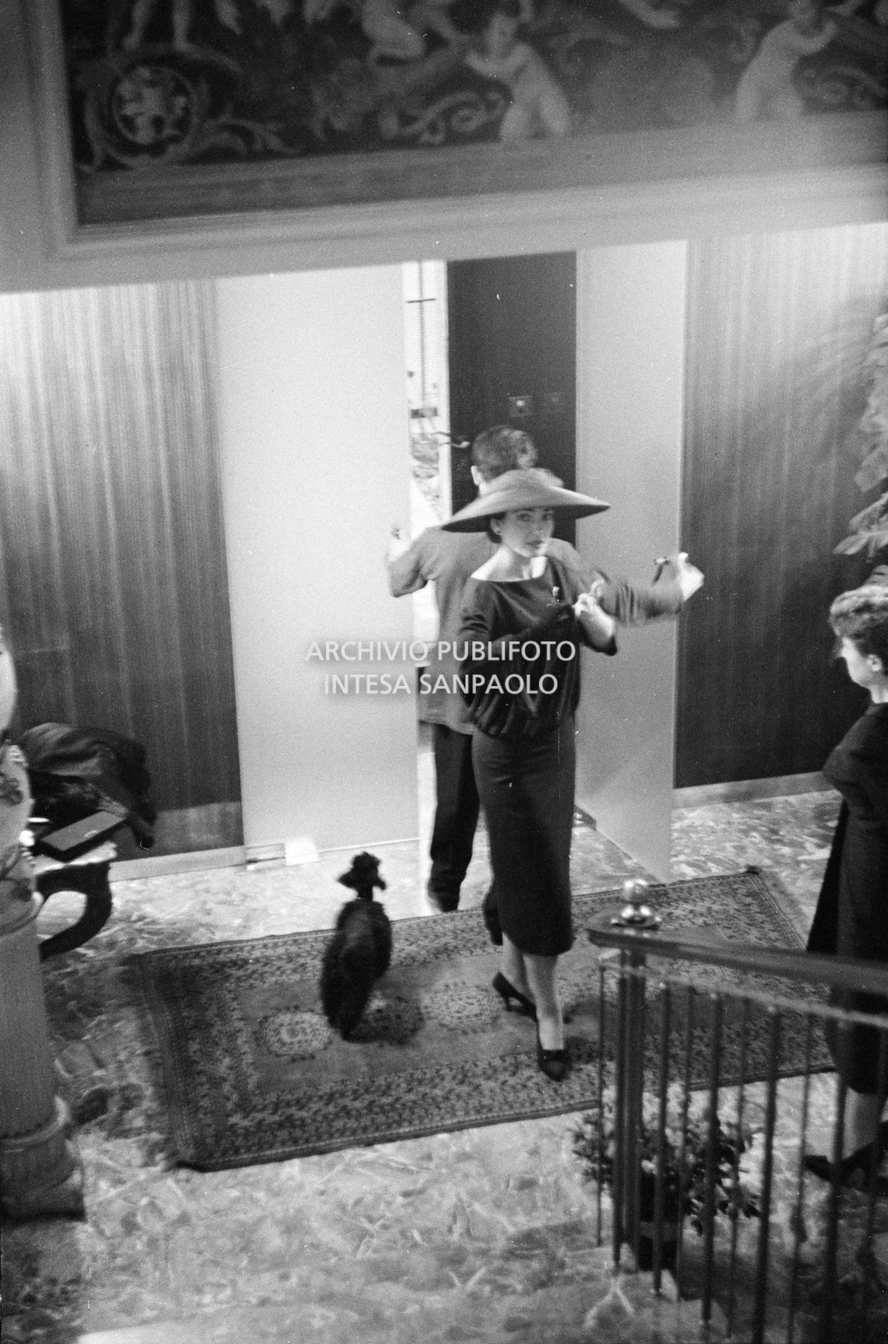 Maria Callas, ritratta nella sua abitazione, indossa un abito e un cappello della sartoria Biki