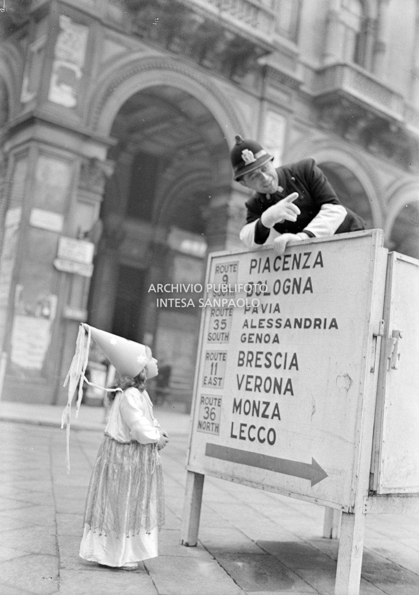 Una bambina travestita da fata turchina chiede informazioni a un vigile in piazza del Duomo a Milano