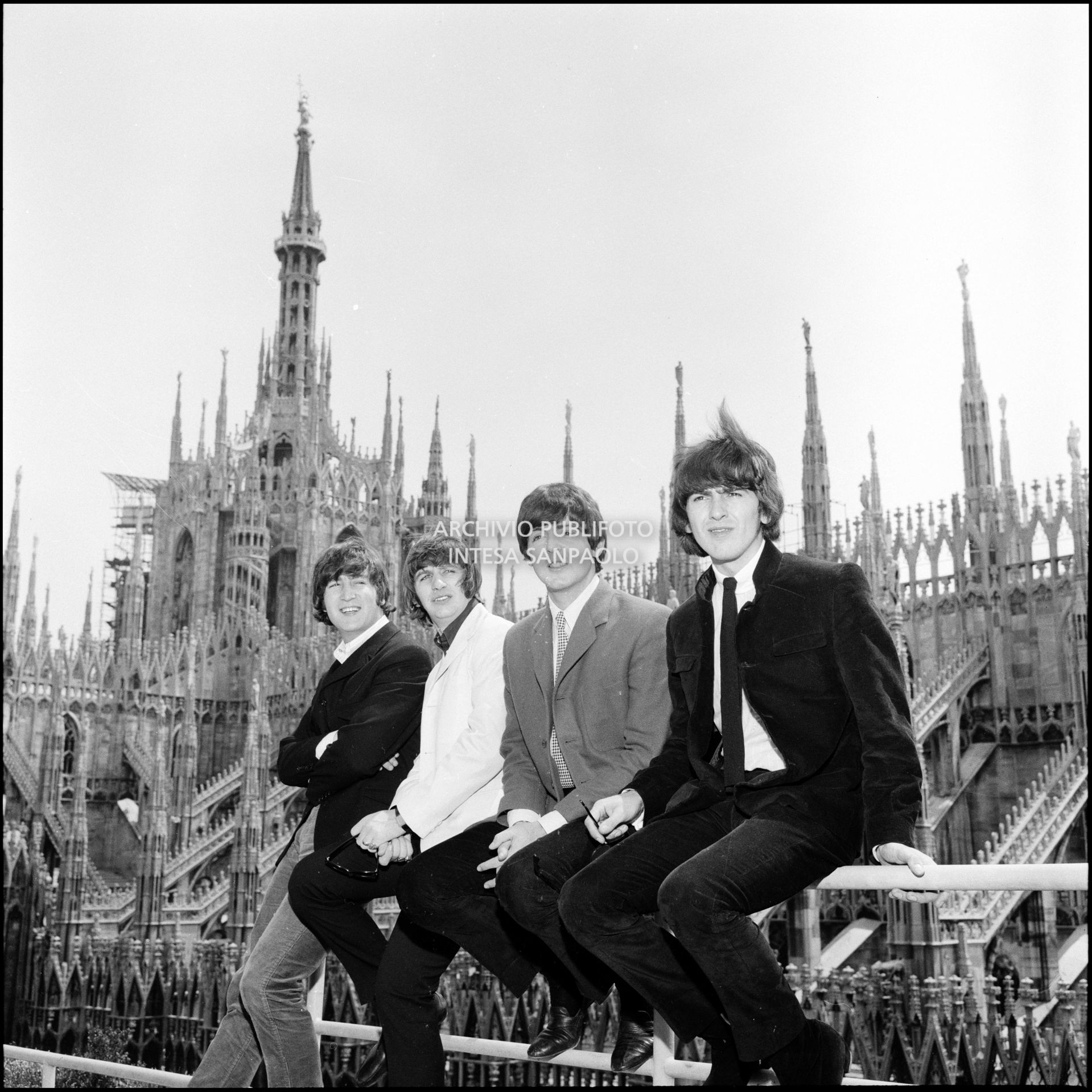 I Beatles ritratti sulla terrazza del Grand Hotel Duomo a Milano; sullo sfondo le guglie della cattedrale