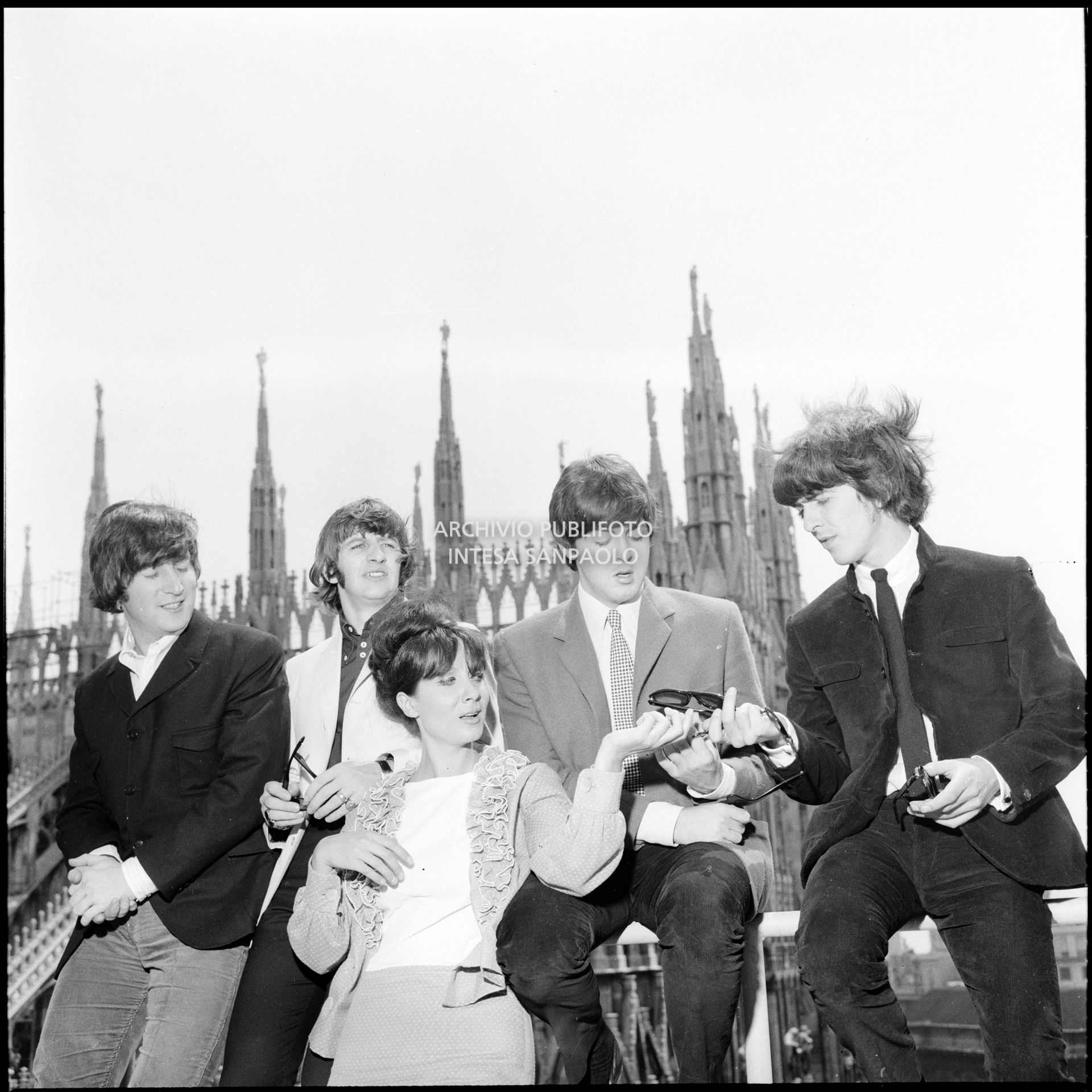 I Beatles con Rossella Como ritratti sulla terrazza del Grand Hotel Duomo a Milano; sullo sfondo le guglie della cattedrale