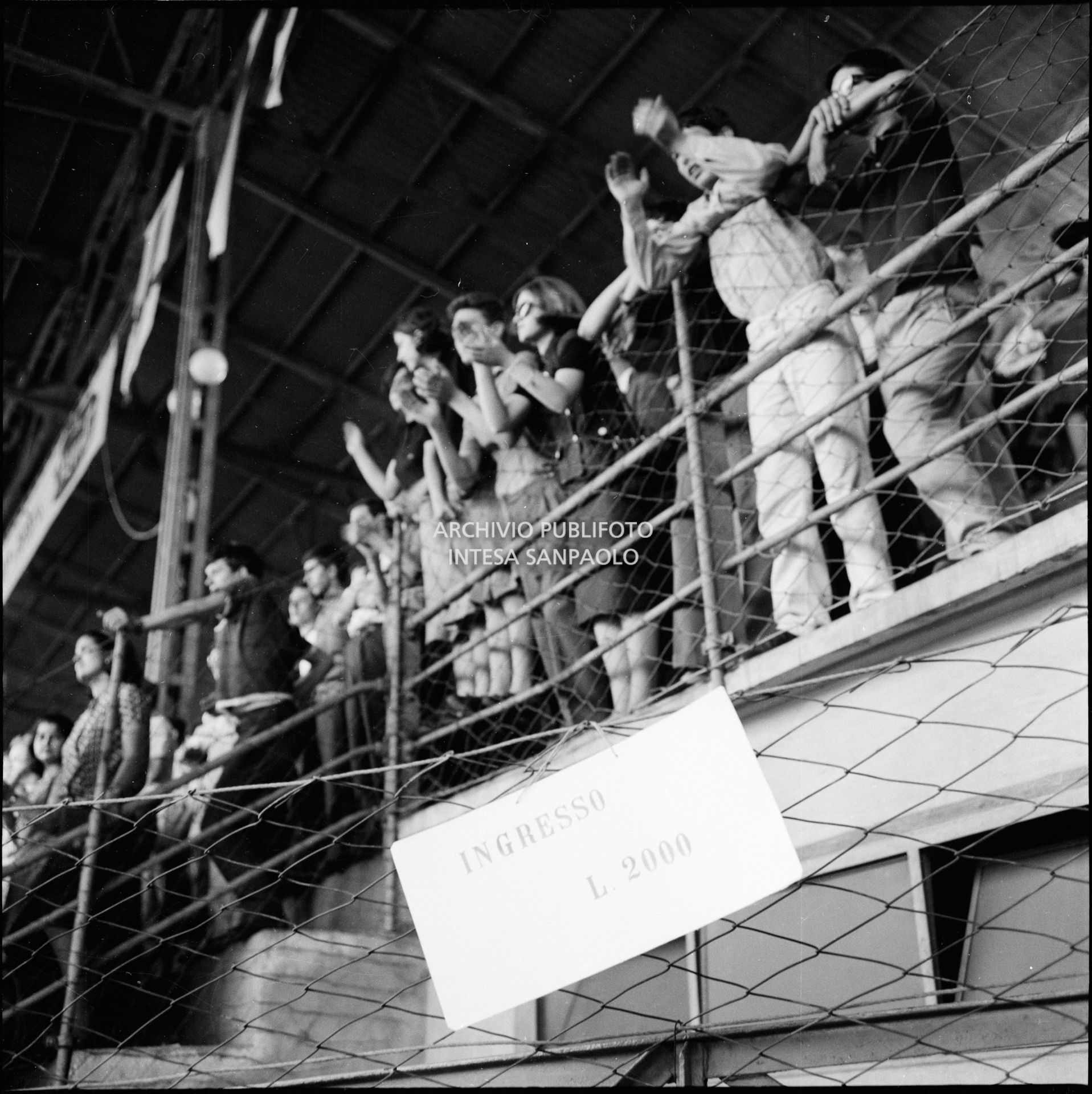 Cartello, con il costo del biglietto per il concerto dei Beatles, esposto al Vigorelli di Milano; sullo sfondo il pubblico sugli spalti