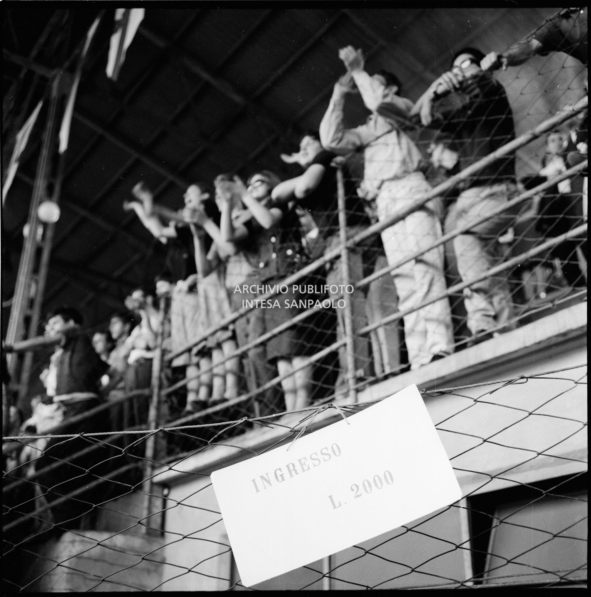 Cartello, con il costo del biglietto per il concerto dei Beatles, esposto al Vigorelli di Milano; sullo sfondo il pubblico sugli spalti