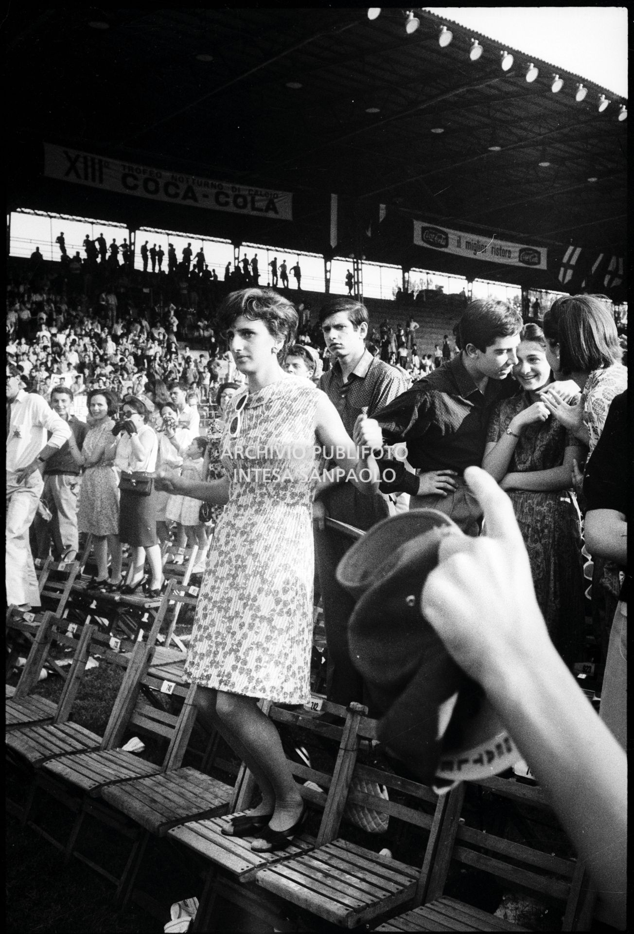 Pubblico in piedi sulle sedie al concerto pomeridiano dei Beatles al Vigorelli di Milano: in primo piano una ragazza balla