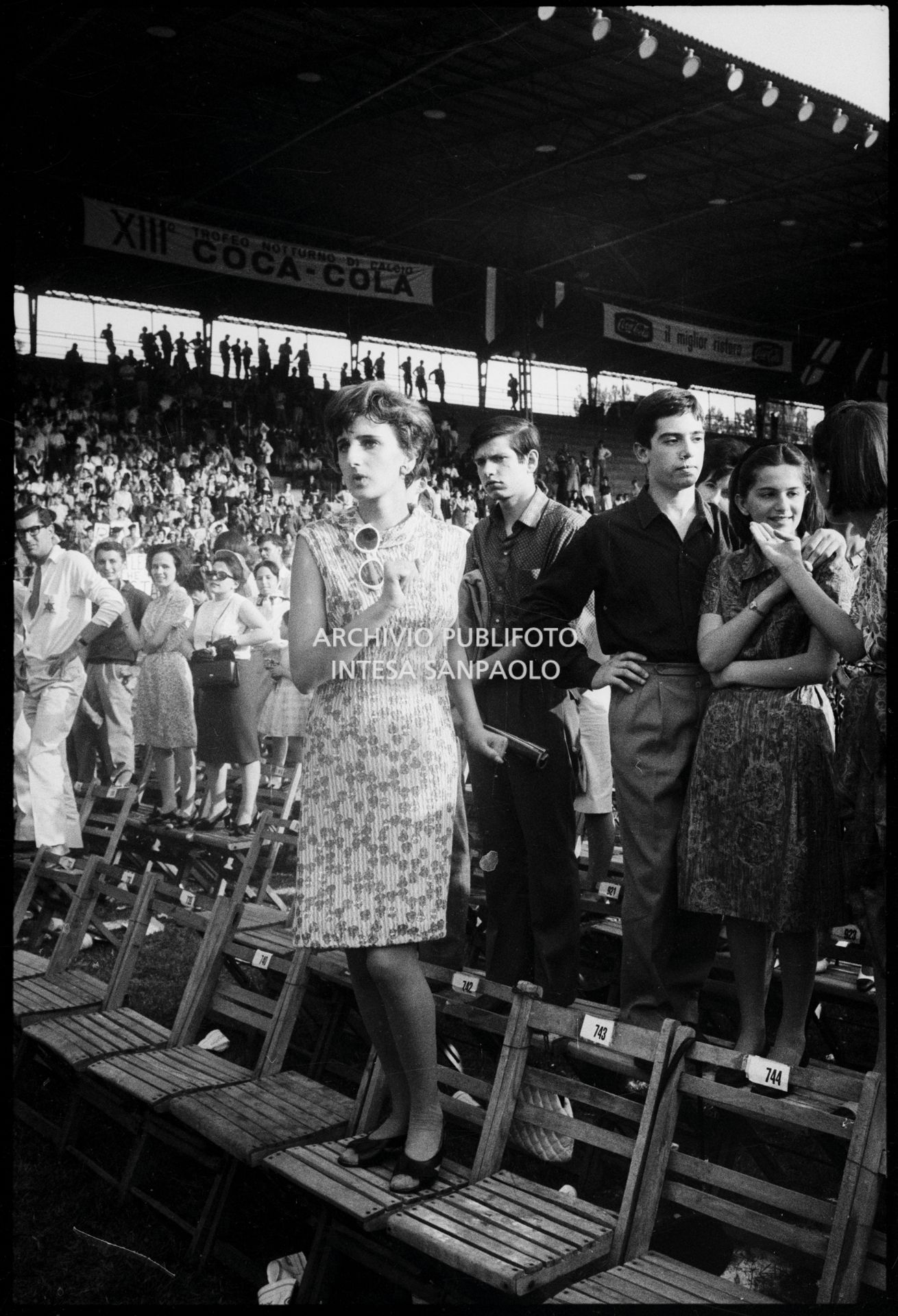 Pubblico in piedi sulle sedie al concerto pomeridiano dei Beatles al Vigorelli di Milano: in primo piano una ragazza balla