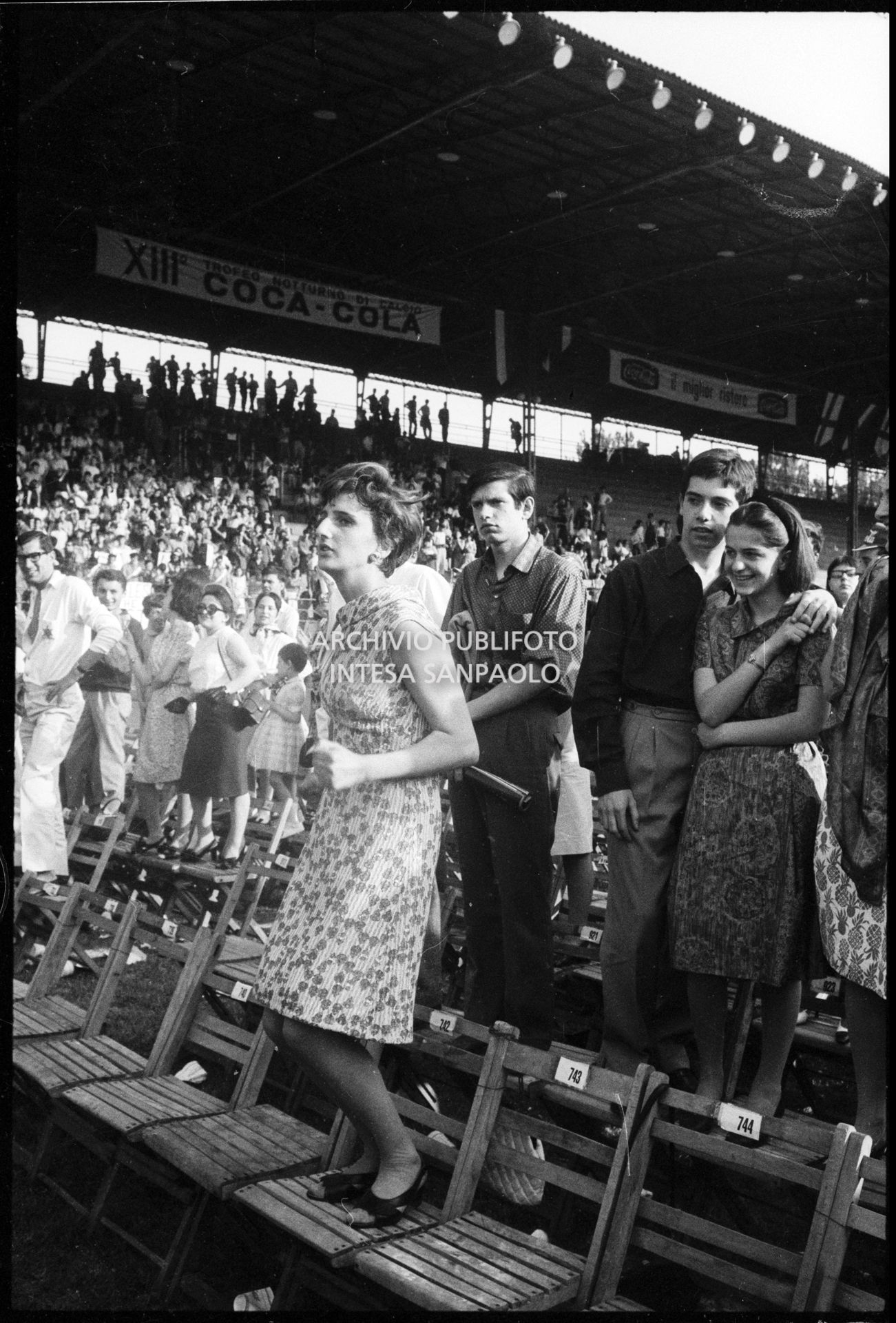 Pubblico in piedi sulle sedie al concerto pomeridiano dei Beatles al Vigorelli di Milano: in primo piano una ragazza balla