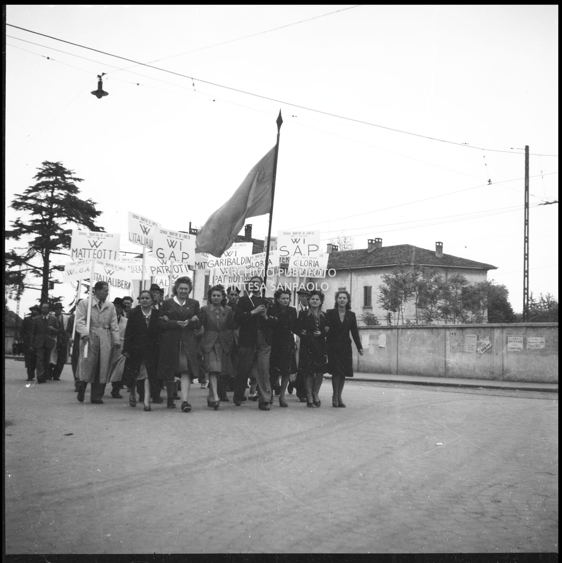 Un gruppo di persone con cartelli della Cellula Martiri di Loreto di Sesto San Giovanni e con la bandiera rossa si avvia al grande comizio a Sesto San Giovanni per la celebrazione della festa del Primo maggio nella sesta giornata di insurrezione generale