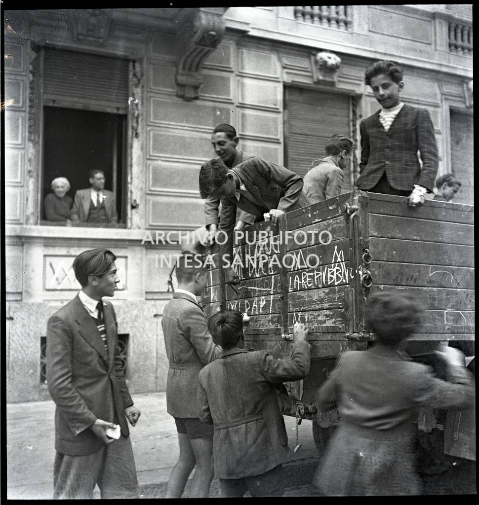 Un gruppo di bambini scrive con il gesso sul cassone di un camion, visibili le scritte "ʍ [abbasso] la Repubblica", "ʍ [abbasso] il duce"