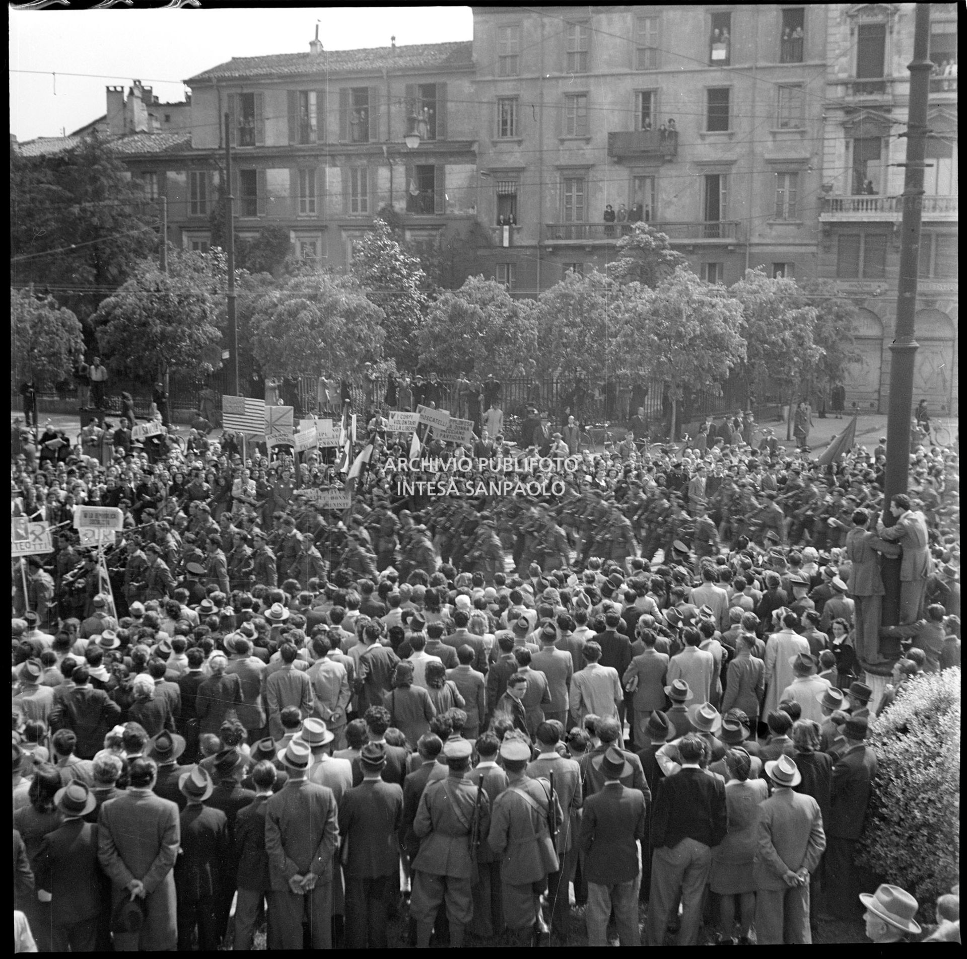 Folla in largo Cairoli a Milano assiste alla sfilata delle formazioni partigiane