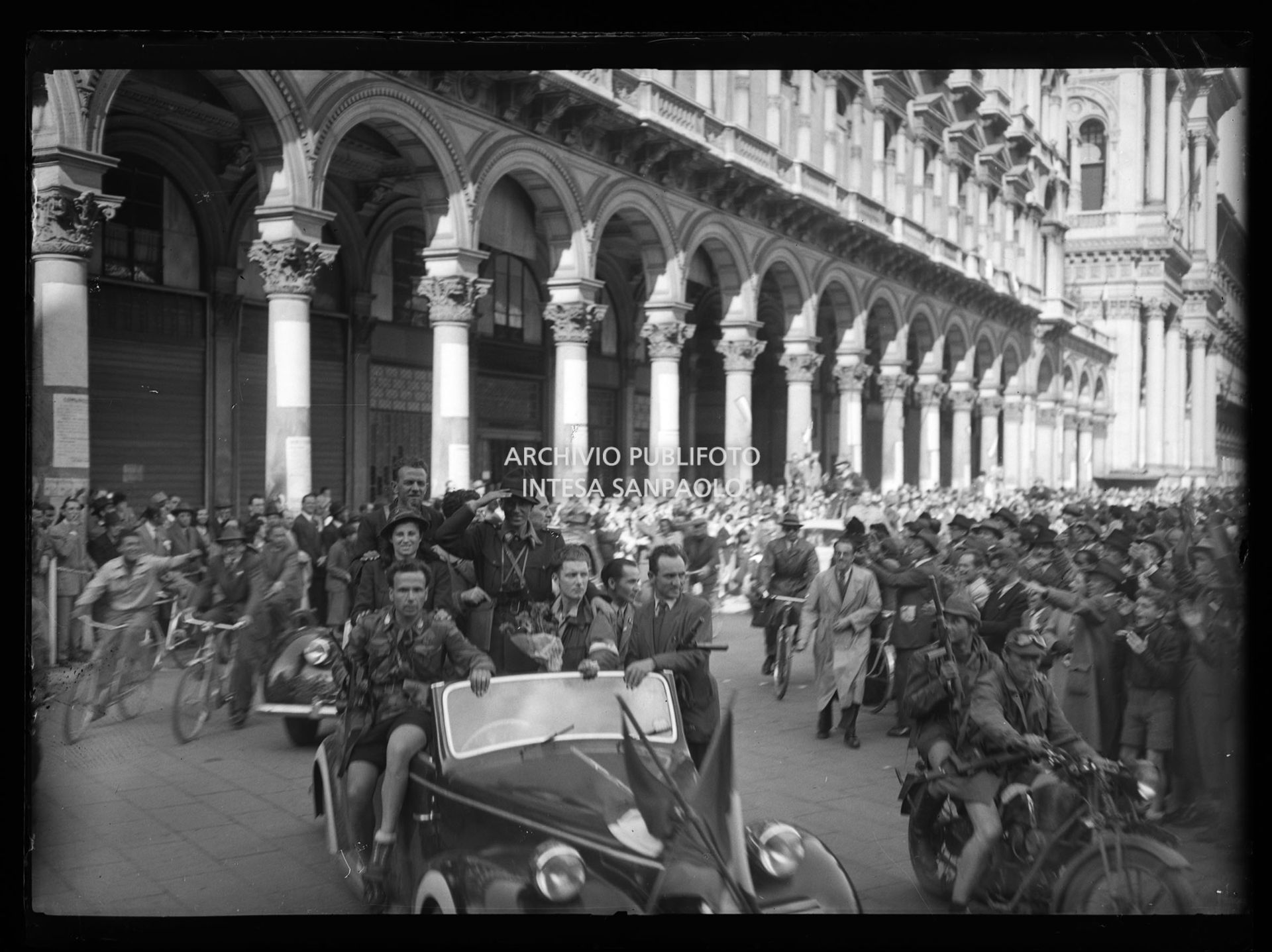 La colonna della Valsesia e dell'Ossola arriva in piazza del Duomo a Milano accolta dalla folla festante: sull'auto tra gli altri Cino Moscatelli (con il cappello da alpino) e Teresa Mondini Maruska