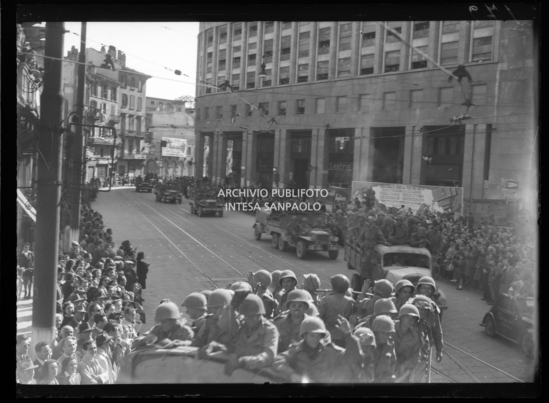 Colonna di mezzi delle truppe americane alleate sfilain piazza San Babila a Milano accolta dalla folla nella settima giornata di insurrezione generale