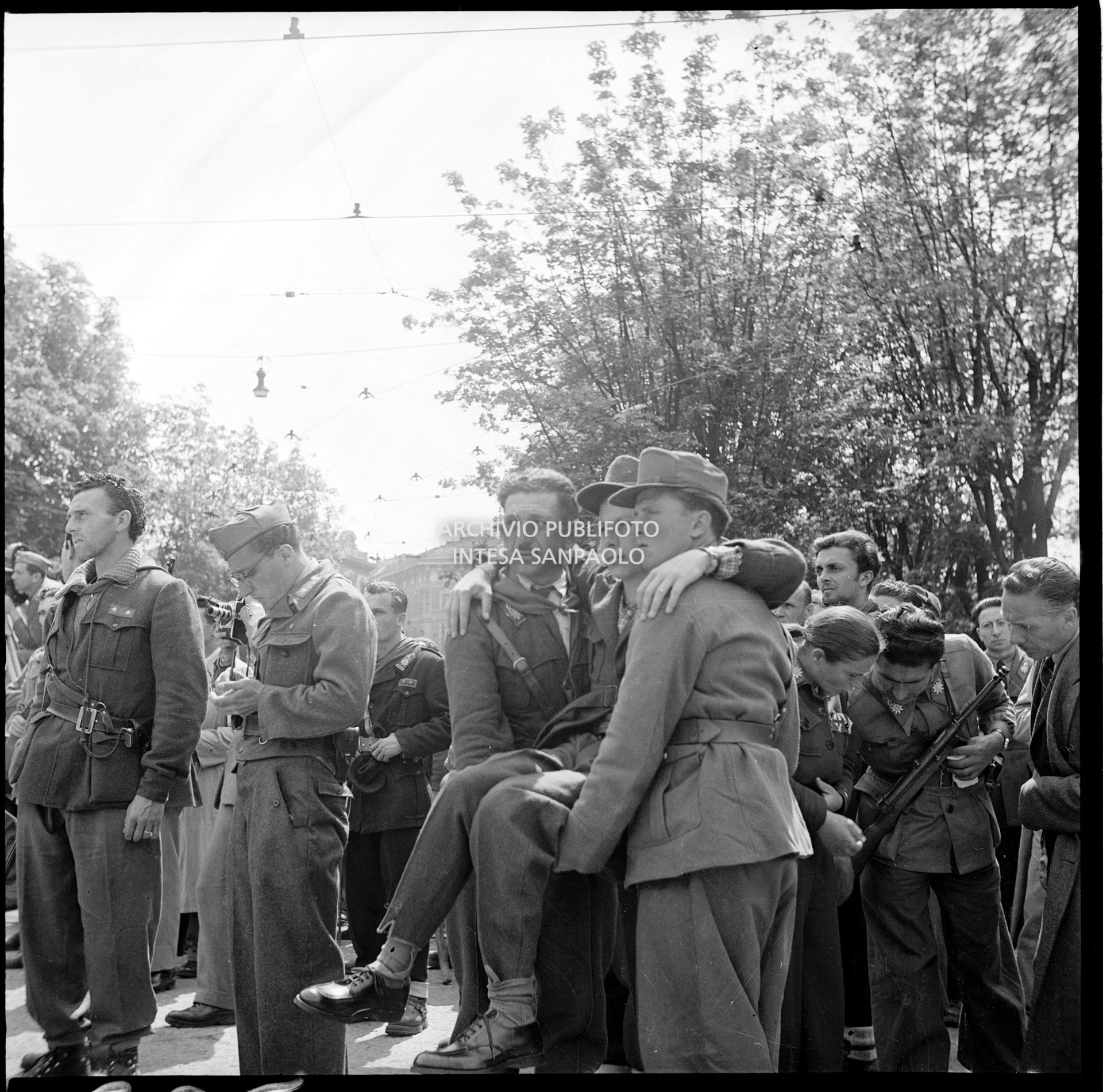 Un gruppo di partigiani, tra cui un ragazzo ferito portato a braccia dai suoi compagni, durante la manifestazione  in piazza Castello a Milano in onore delle formazioni partigiane