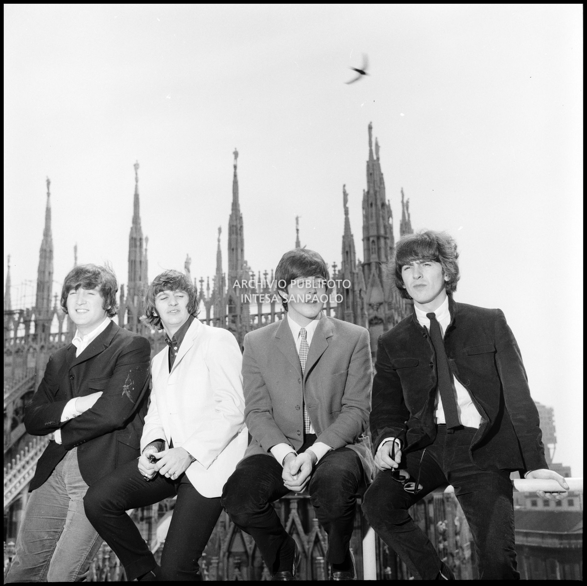 I Beatles ritratti sulla terrazza del Grand Hotel Duomo a Milano; sullo sfondo le guglie della cattedrale