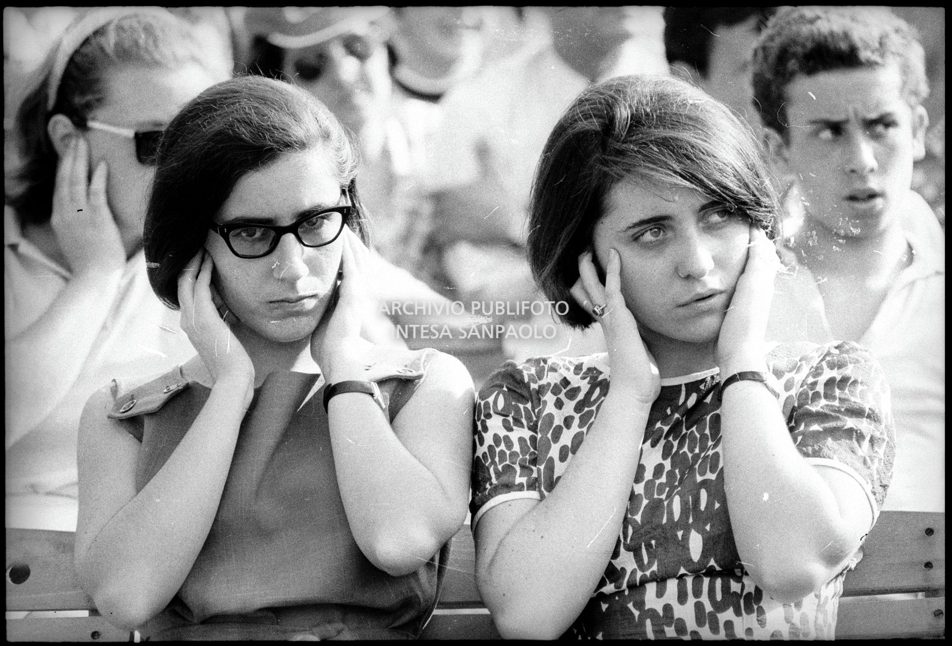 Tre ragazze tra il pubblico al concerto pomeridiano dei Beatles al Vigorelli di Milano, si tappano le orecchie presumibilmente per il forte volume