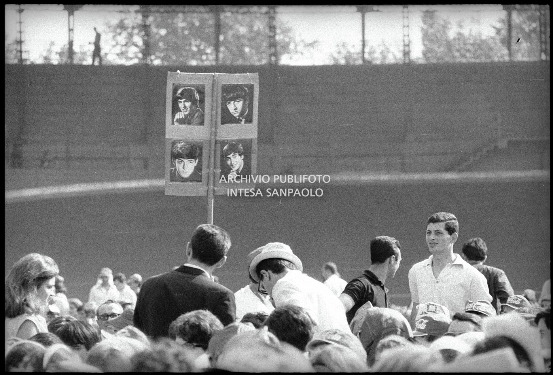 Cartello con le fotografie dei Fab Four sorretto dal pubblico al Vigorelli di Milano in attesa dell'inizio del concerto pomeridiano dei Beatles
