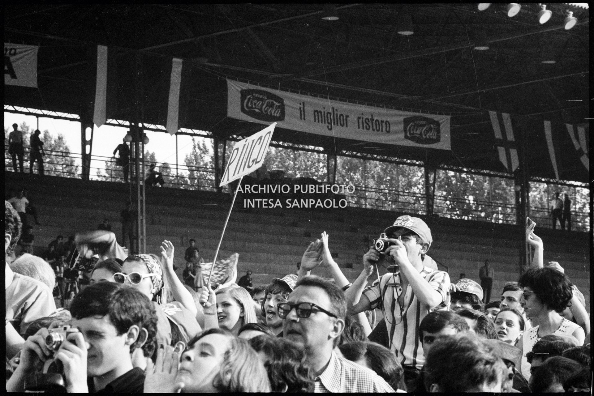 Pubblico al concerto pomeridiano dei Beatles al Vigorelli di Milano; molti ragazzi con la macchina fotografica, un cartello con la scritta "Ringo"