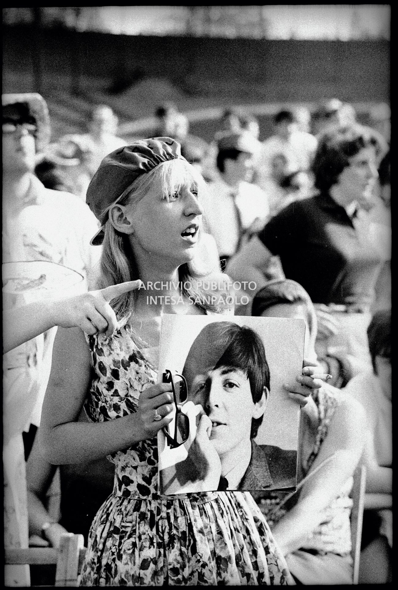 Una ragazza tra il pubblico al concerto pomeridiano dei Beatles al Vigorelli di Milano tiene in mano la fotografia di Paul McCartney