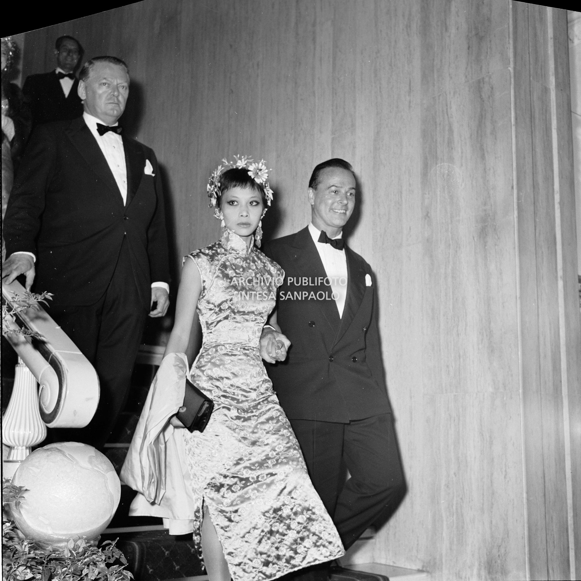 Oliver Messel a braccetto con Jacquline Chan al ricevimento organizzato da Elsa Maxwell in onore di Maria Callas