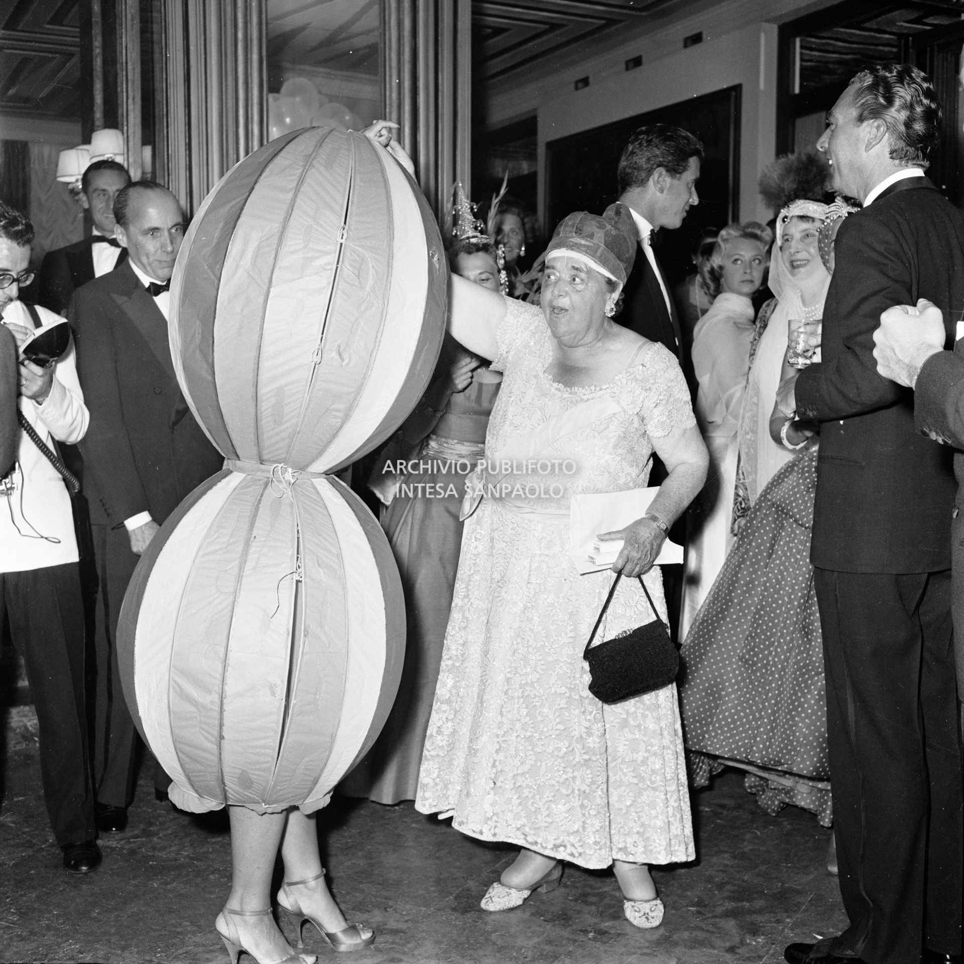 Elsa Maxwell dà la mano a Miss Maria Salata Philips avvolta da un curioso costume al ricevimento organizzato dalla giornalista americana in onore di Maria Callas