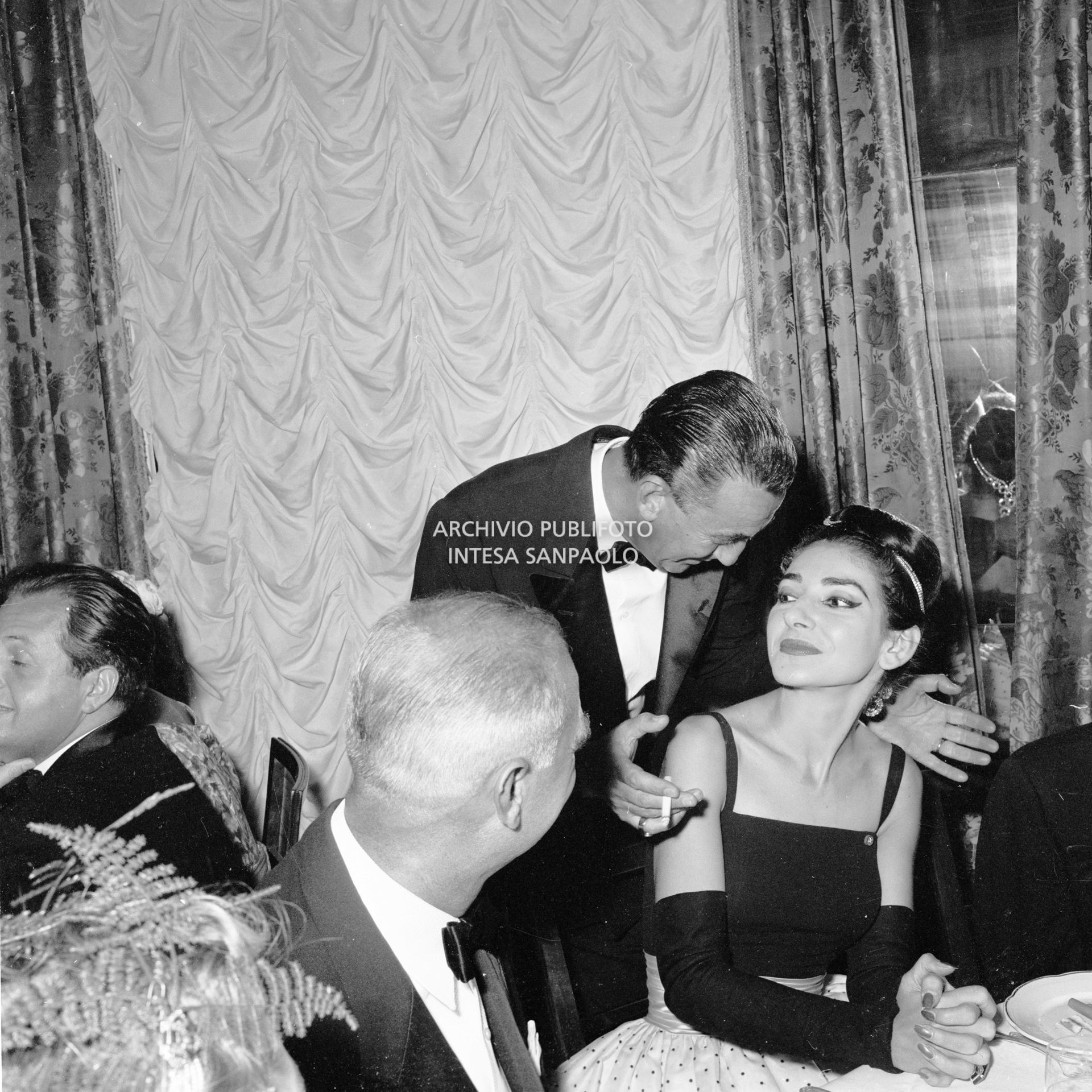 Maria Callas parla con Luchino Visconti al ricevimento organizzato da Elsa Maxwell in onore della soprano