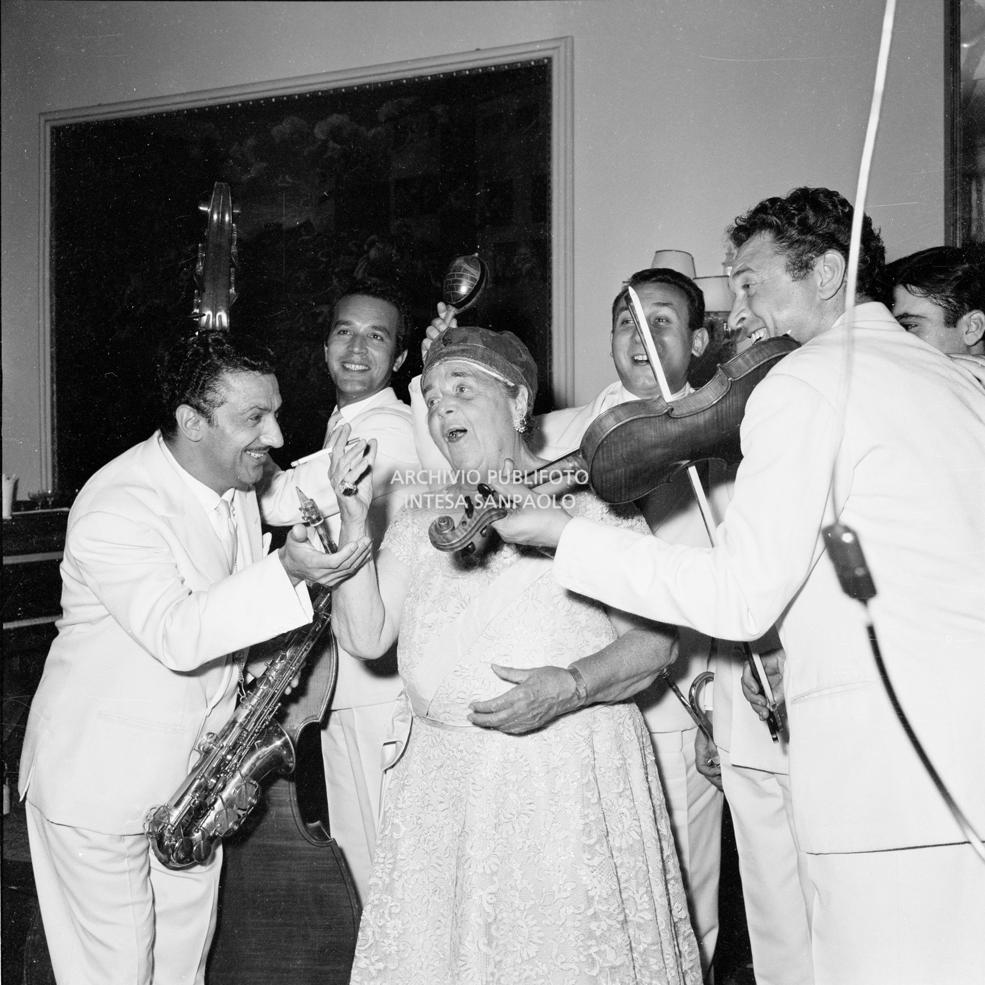 Elsa Maxwell canta accompagnata dai musicisti che intrattengono gli ospiti al ricevimento che la giornalista americana ha organizzato in onore di Maria Callas