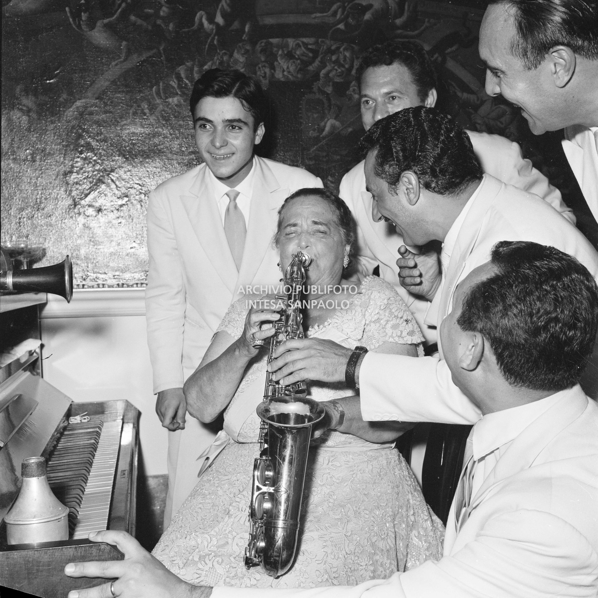 Elsa Maxwell suona il sassofono accompagnata dai musicisti che intrattengono gli ospiti al ricevimento che la giornalista americana ha organizzato in onore di Maria Callas