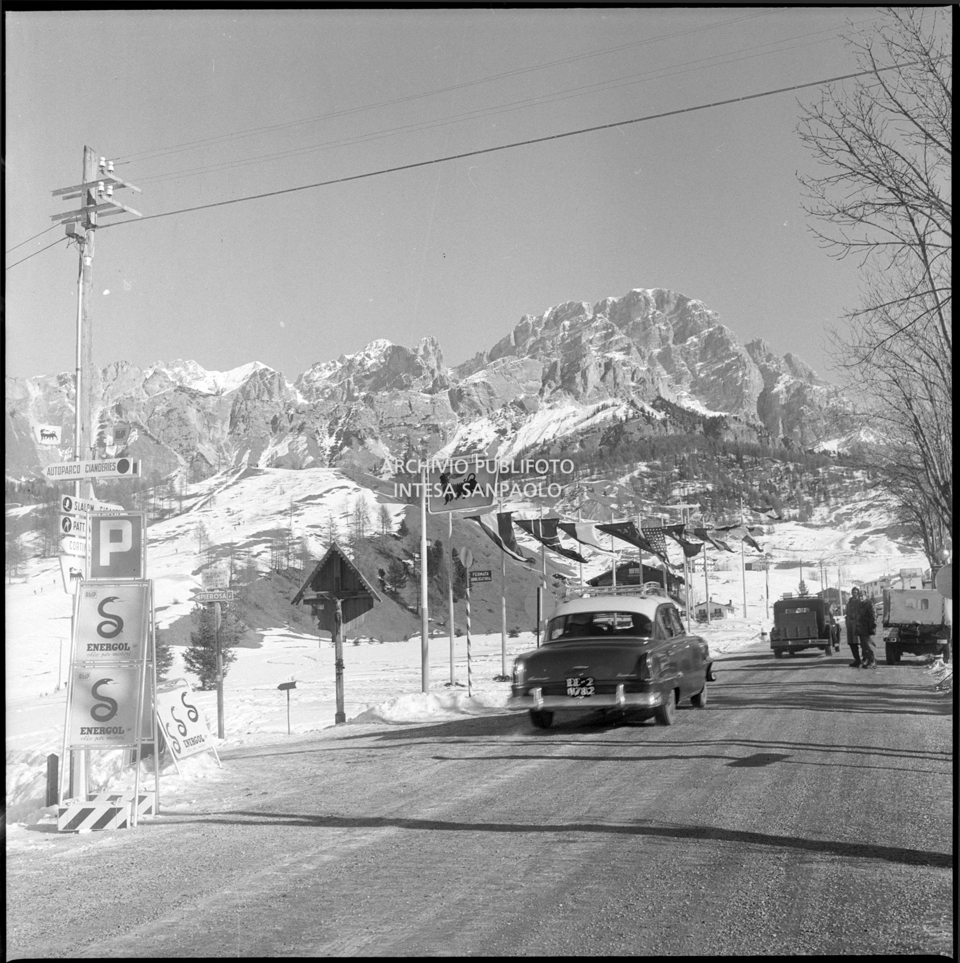 Un'Opel Kapitan sulla strada regionale delle Dolomiti imbandierata nei pressi di Cortina d'Ampezzo nel periodo dei VII Giochi olimpici invernali