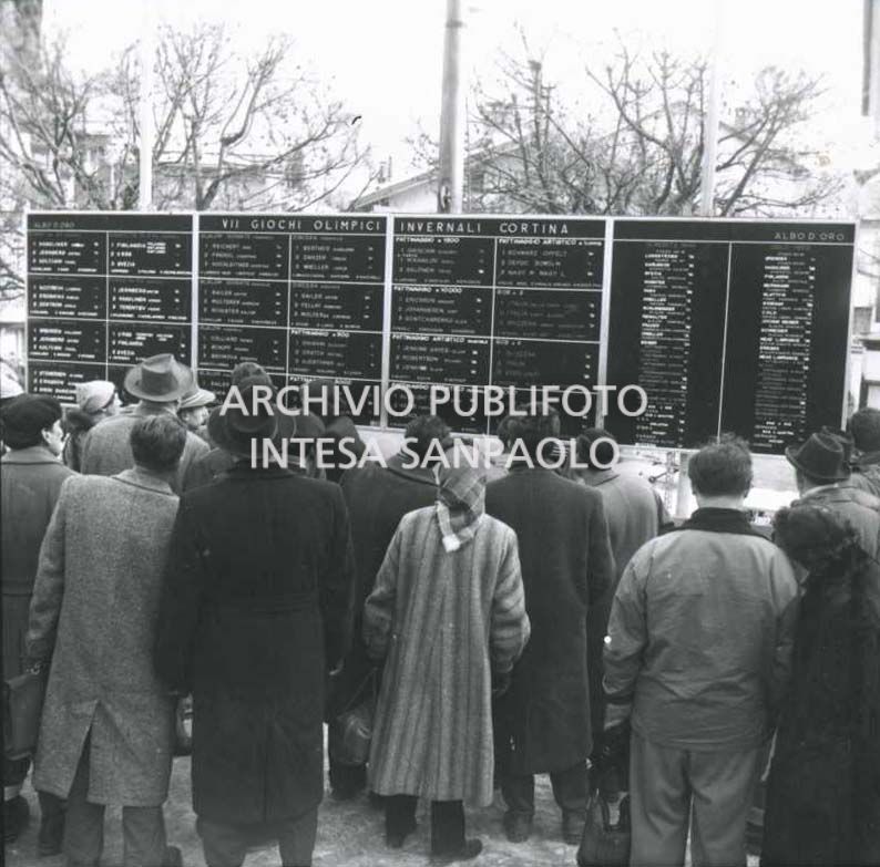Folla davanti ai pannelli con l'albo d'oro dei VII Giochi olimpici invernali a Cortina d'Ampezzo