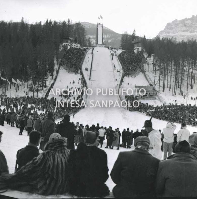 Spettatori assistono a una gara di salto con gli sci al Trampolino Italia durante i VII Giochi olimpici invernali a Cortina d'Ampezzo