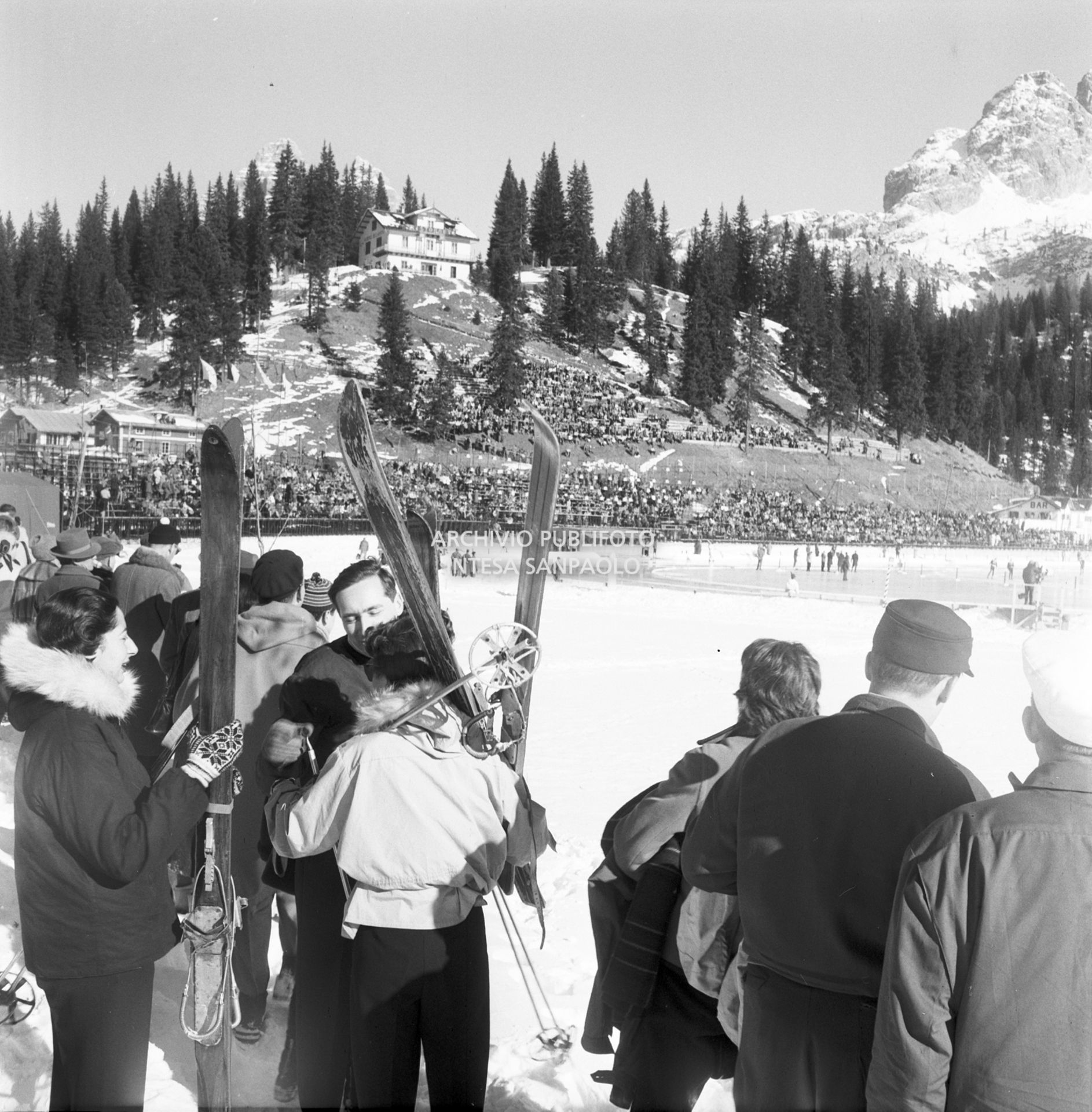 Spettatori, alcuni con gli sci, a bordo della pista per le gare di pattinaggio di velocità sul lago di Misurina ai VII Giochi olimpici invernali