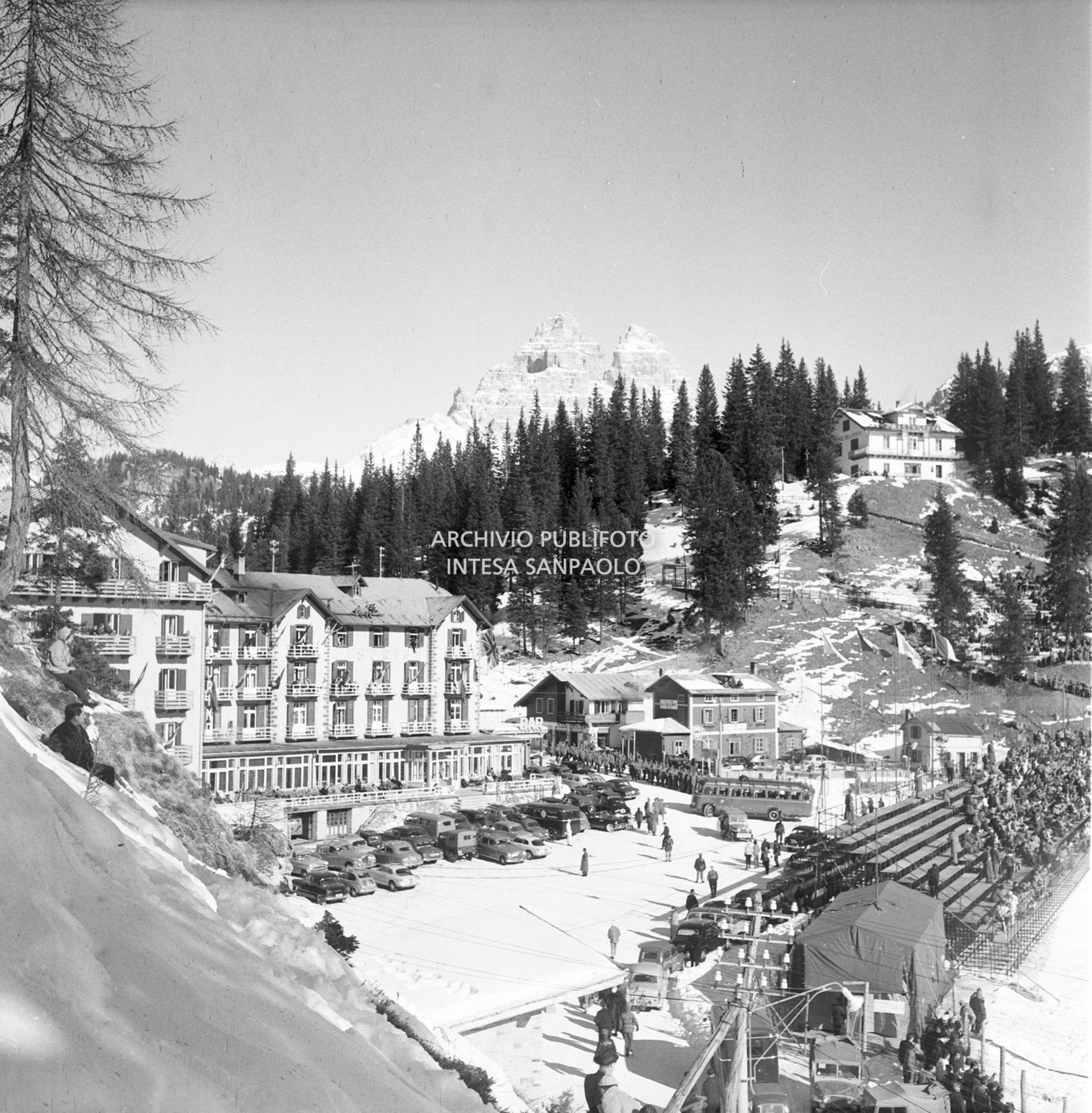 Scorcio del Grand Hotel Misurina, dei mezzi parcheggiati e delle tribune sulla pista di pattinaggio di velocità allestita sul lago di Misurina durante i VII Giochi olimpici invernali