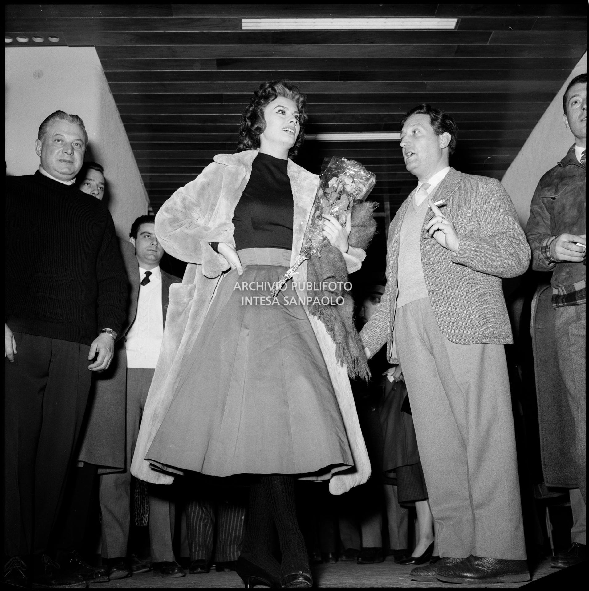 Sophia Loren, al suo arrivo a Cortina d'Ampezzo in occasione dei VII Giochi olimpici invernali, con un mazzo di fiori