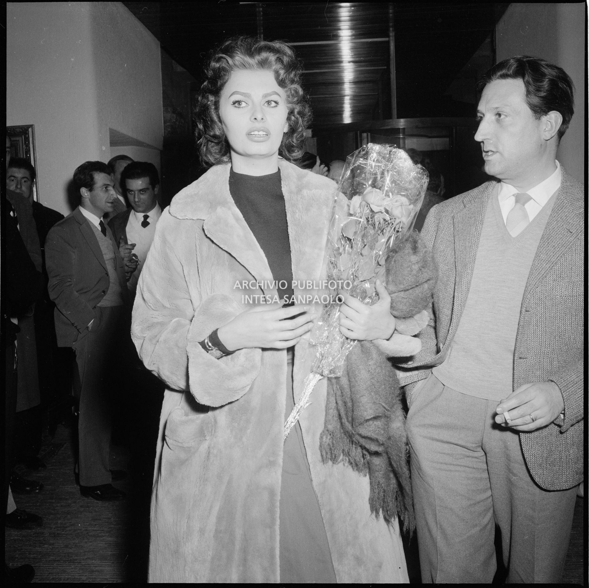 Sophia Loren al suo arrivo a Cortina d'Ampezzo in occasione dei VII Giochi olimpici invernali con un mazzo di fiori in mano