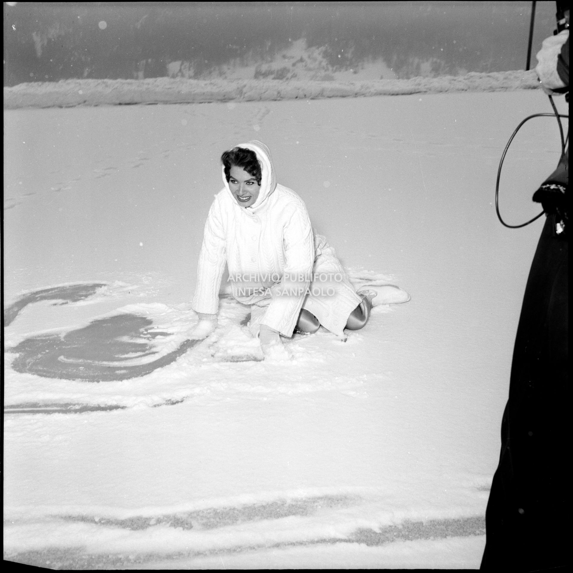 Sophia Loren seduta sul ghiaccio a Cortina d'Ampezzo in occasione della sua visita durante i VII Giochi olimpici invernali