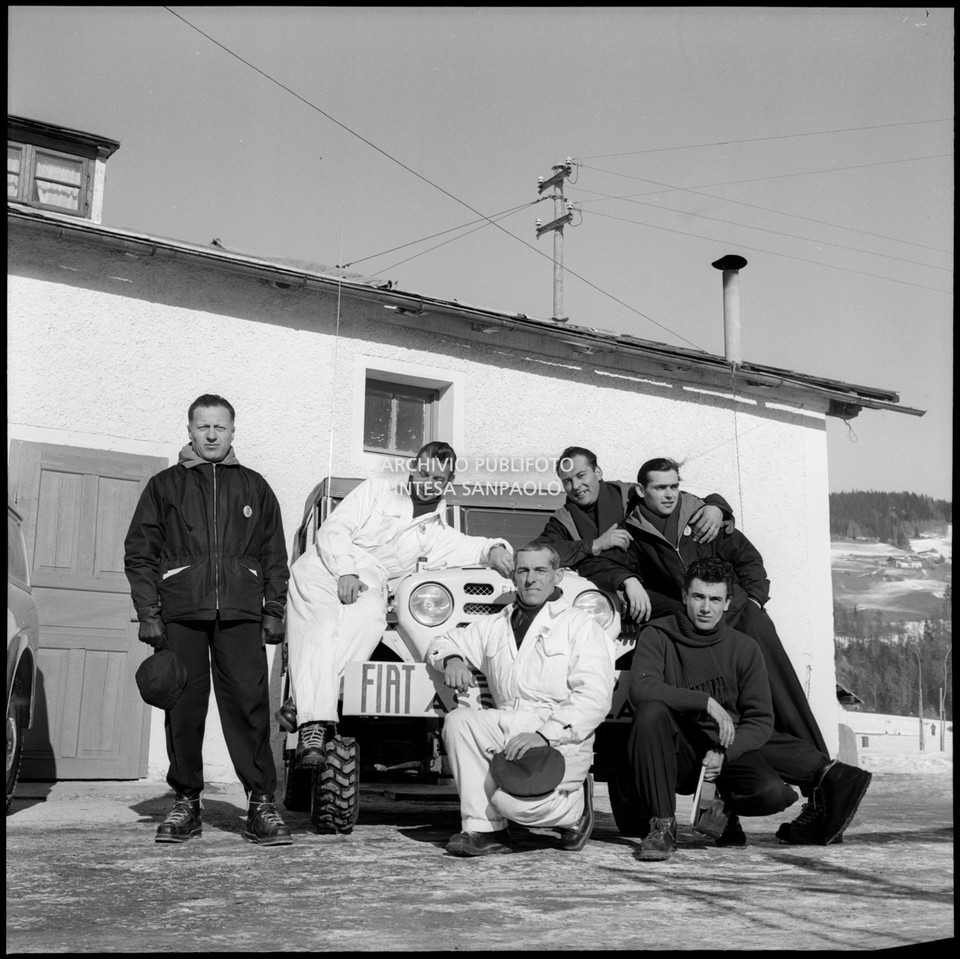 La sciatrice alpina Madeleine Berthod posa con alcuni uomini della Fiat vicino a una Fiat Campagnola presso l'officina allestita per i VII Giochi olimpici invernali